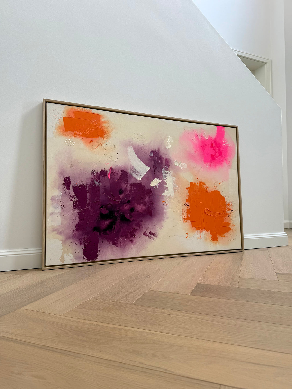 A LATE SUMMER THOUGHT im hellen Wohnraum, auf Holzboden an eine weiße Wand gelehnt, mit Eichenrahmen und abstrakten Farbflächen in Orange, Violett und Neonpink.