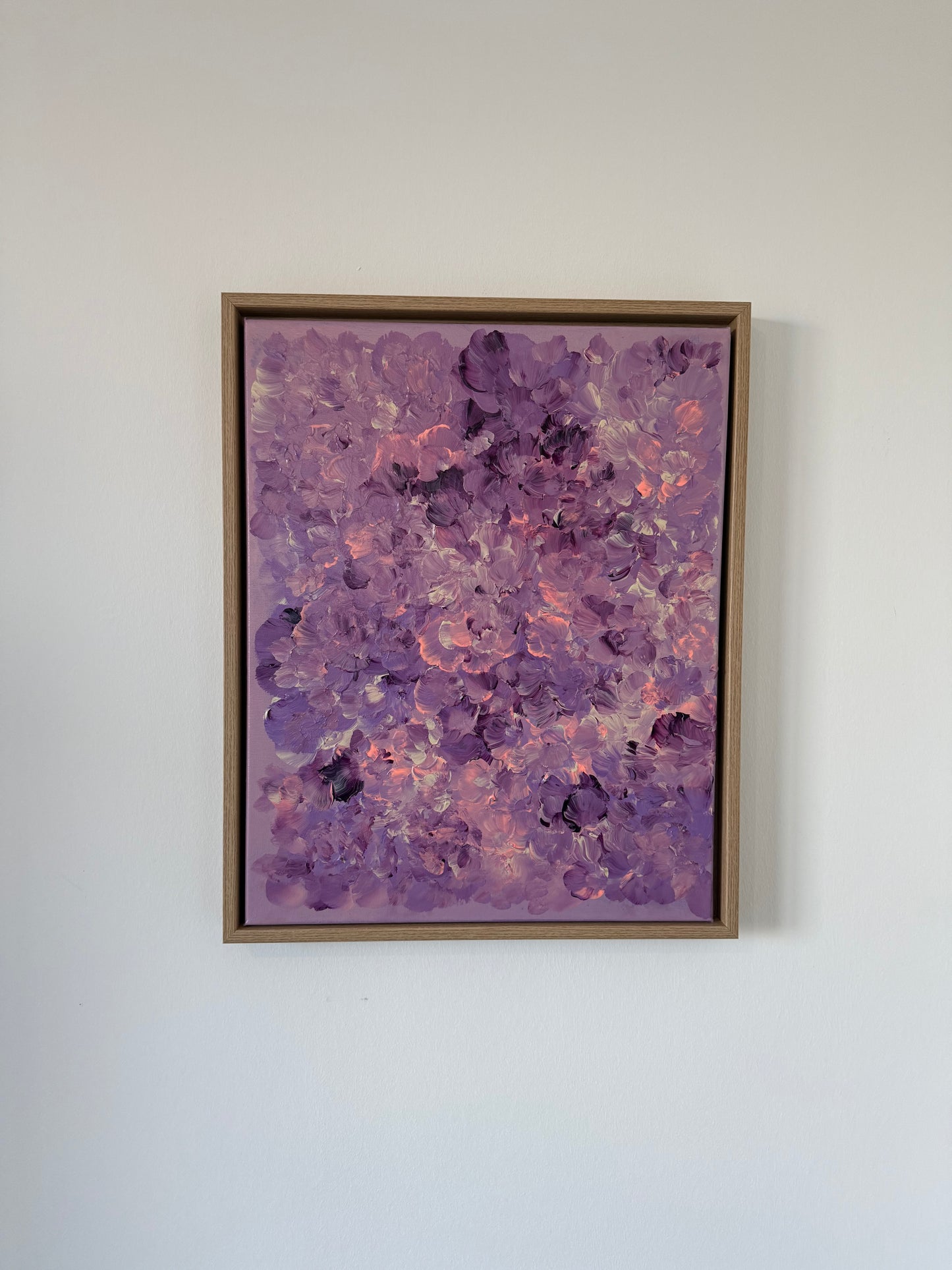 Abstraktes florales Kunstwerk auf Leinwand in Lila, Flieder und Rosé, mit leicht strukturierter Oberfläche, an weißer Wand hängend