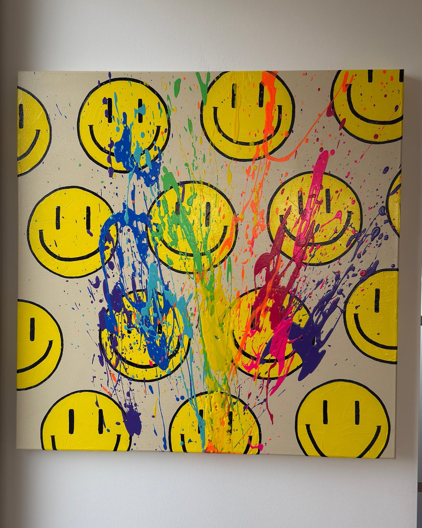 abstraktes Kunstwerk mit gelben Happy-Faces beigem Hintergrund und Regenbogen-Farbspritzern