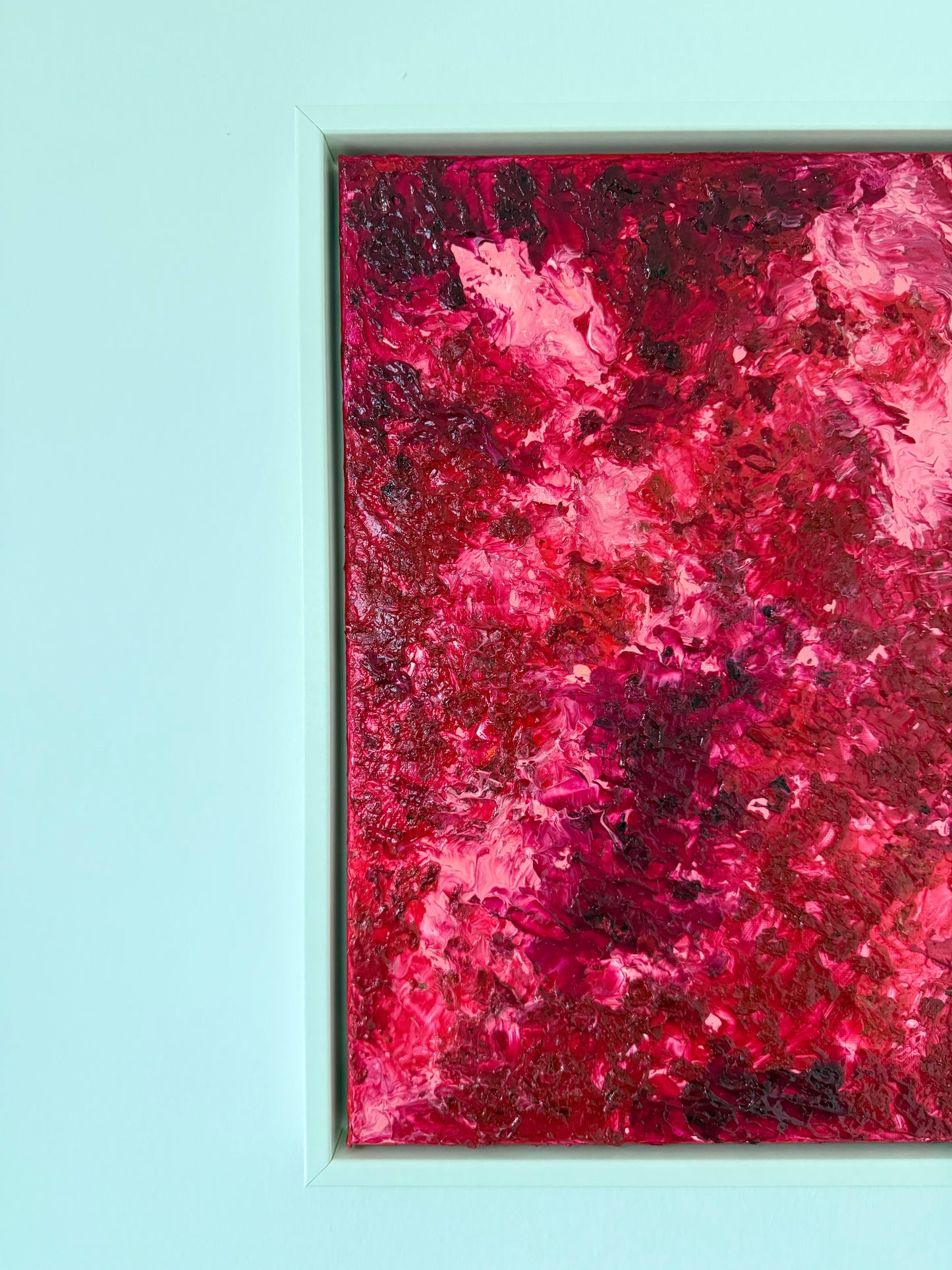 Nahaufnahme eines abstrakten Mixed-Media-Kunstwerks mit ausgeprägter Oberflächenstruktur und kräftiger Farbwirkung, teilweise gerahmt in Weiß.