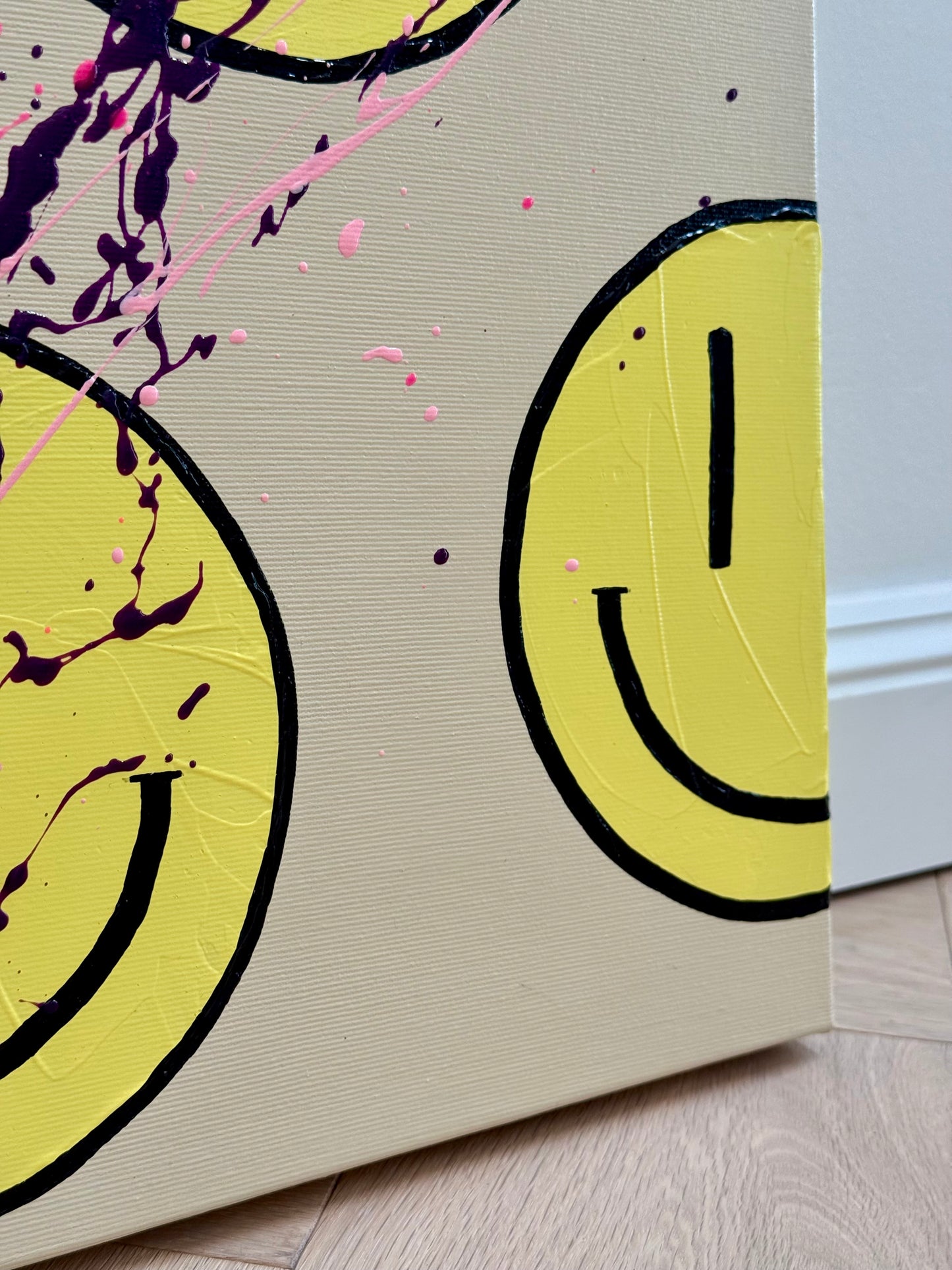 Detailansicht von HAPPY #25 mit einem gelben Happy-Face auf hellem Hintergrund und feinen Farbspritzern als moderne abstrakte Acrylkunst.