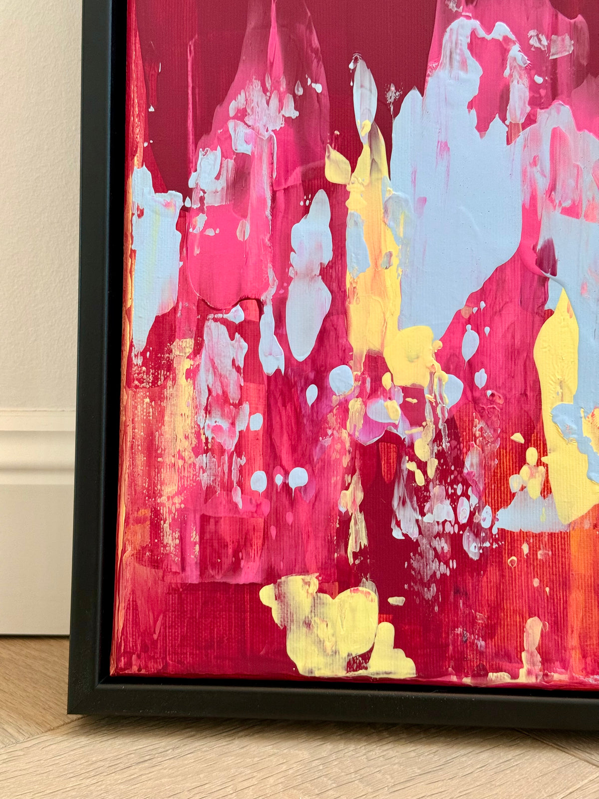Farbenfrohe abstrakte Wandkunst EVOLVING #2 mit expressiver Struktur, leuchtenden Pinktönen und kontrastreichem Blau im schwarzen Rahmen