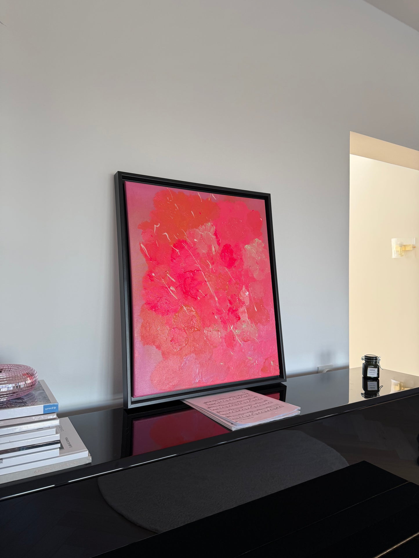 Pinkes abstraktes Kunstwerk auf Leinwand mit texturreicher Oberfläche und Glanz, modernes Acrylbild auf schwarz lackiertem Klavier positioniert