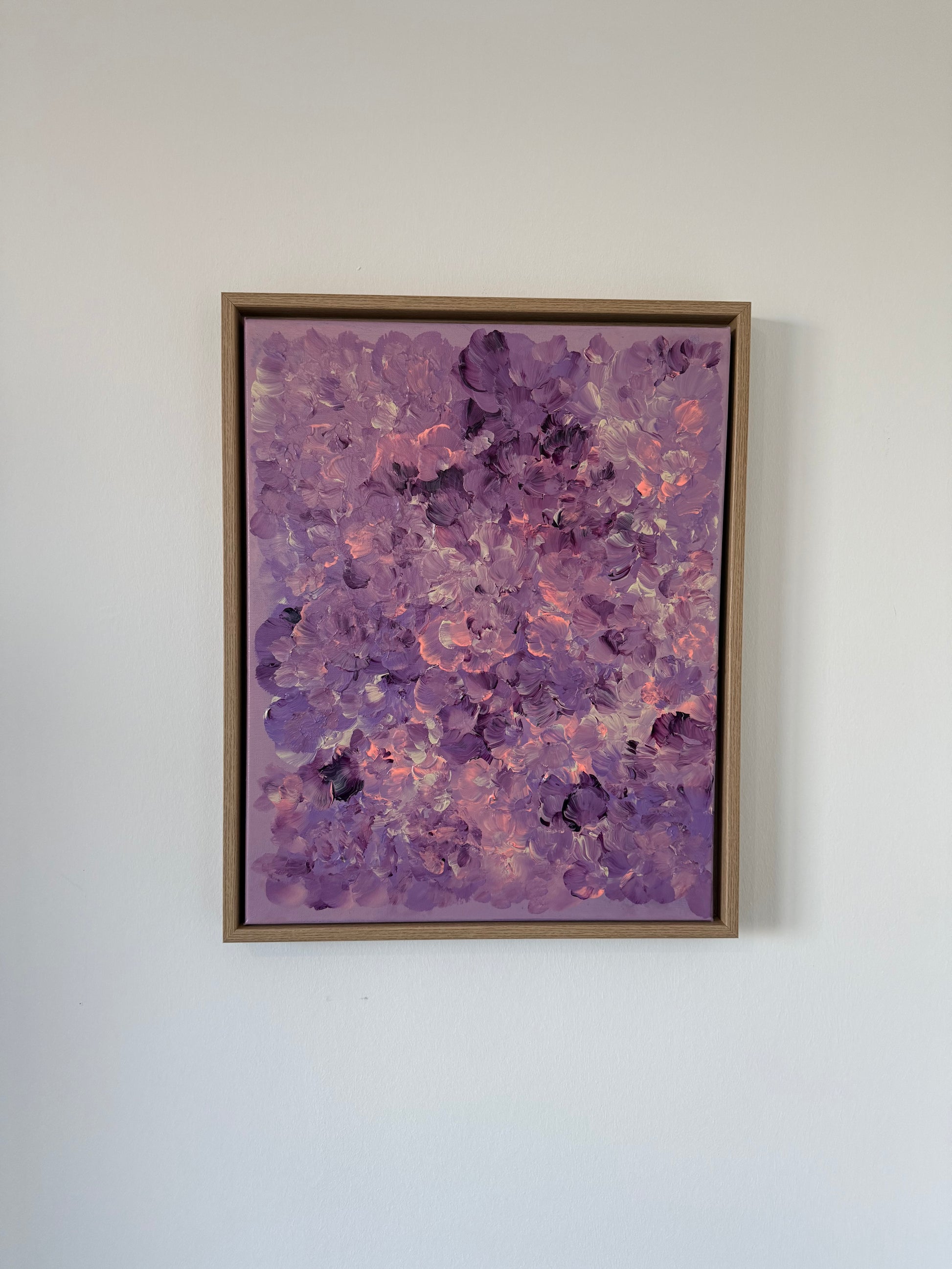 Abstraktes florales Kunstwerk auf Leinwand in Lila, Flieder und Rosé, mit leicht strukturierter Oberfläche, an weißer Wand hängend