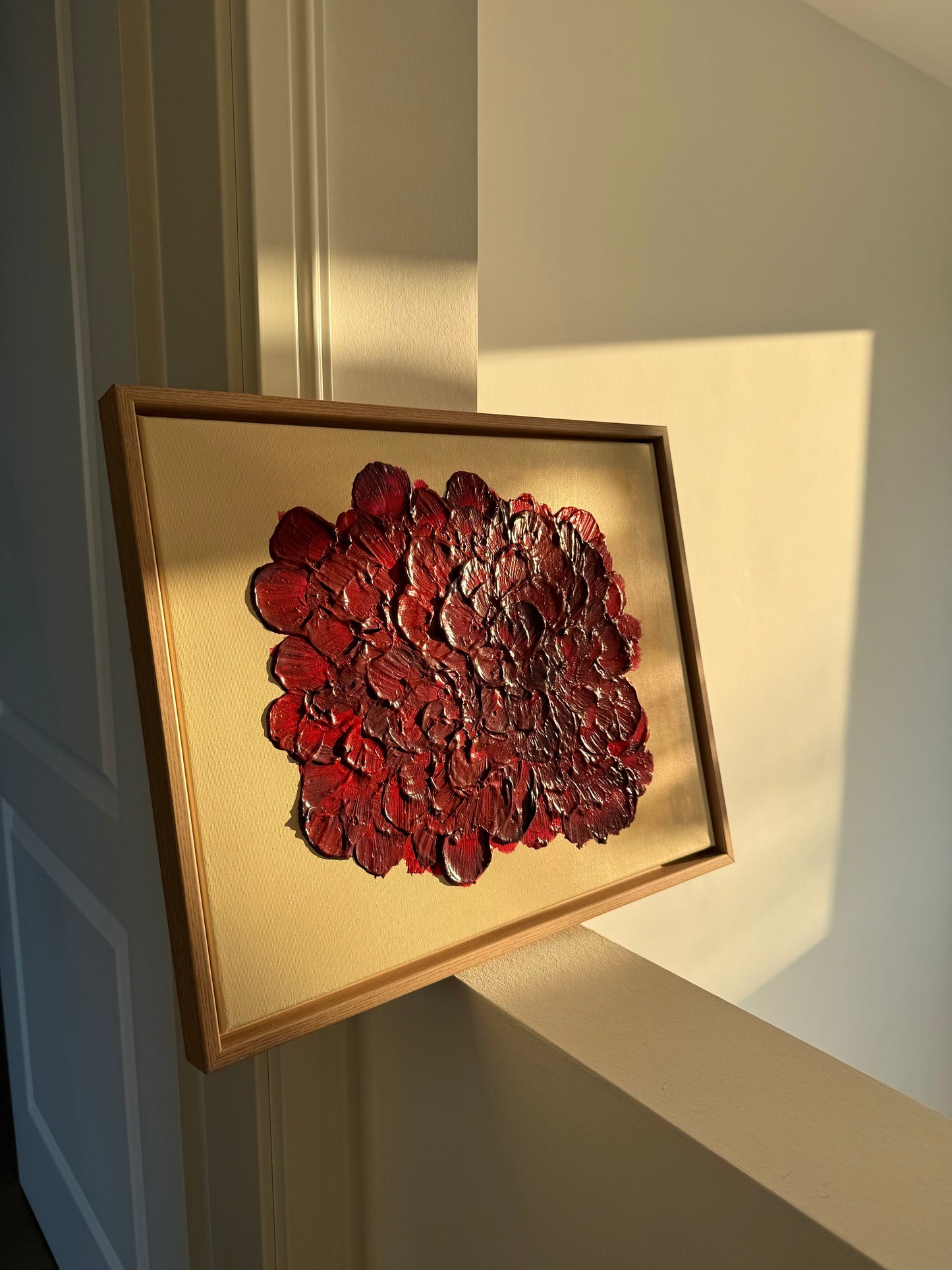 Abstraktes florales Acrylkunstwerks mit stark strukturierter Oberfläche in Tiefrot und Bordeaux in warmen Sonnenlicht