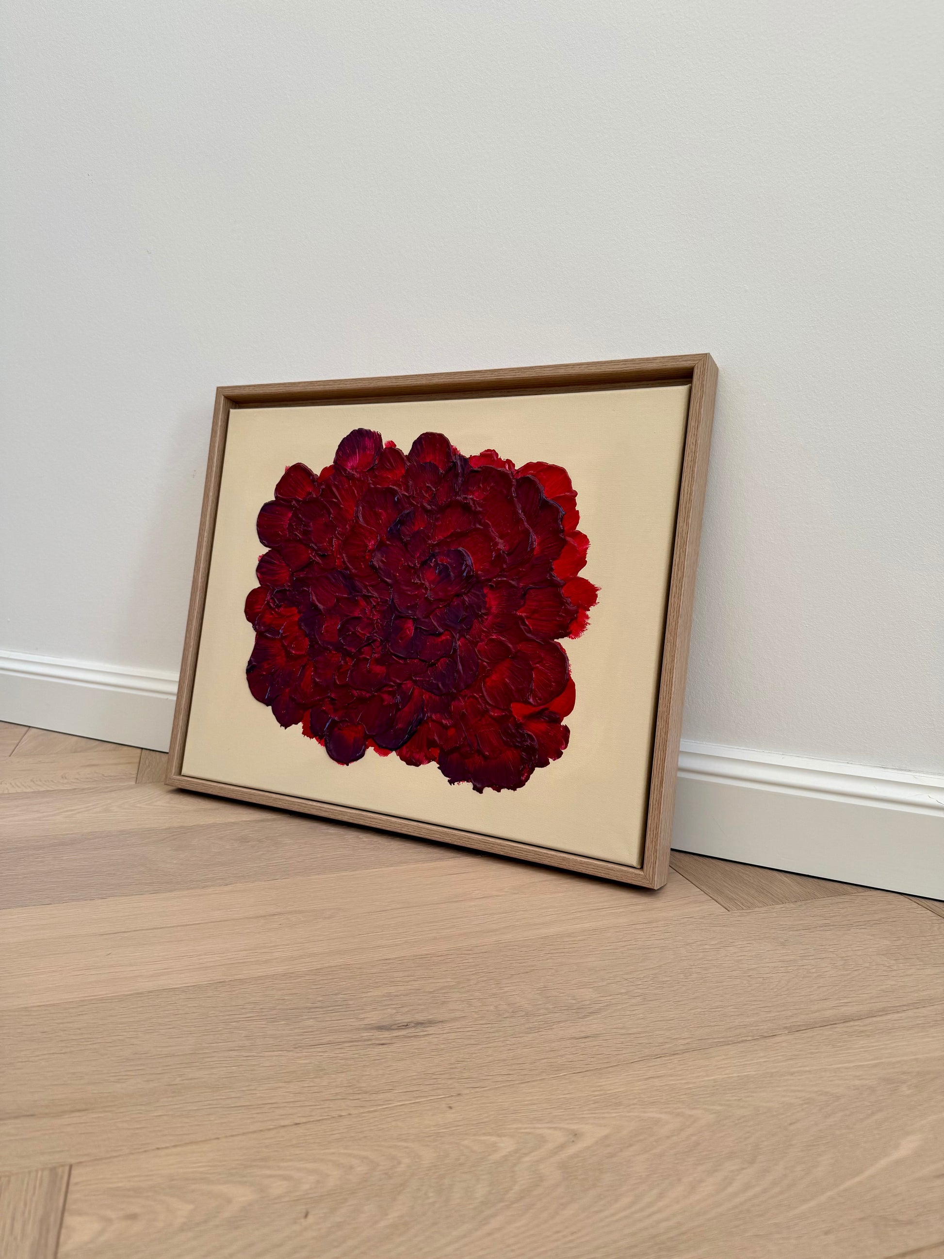 Abstraktes florales Wandbild in Rot- und Burgundertönen, gerahmt und minimalistisch im Wohnraum inszeniert