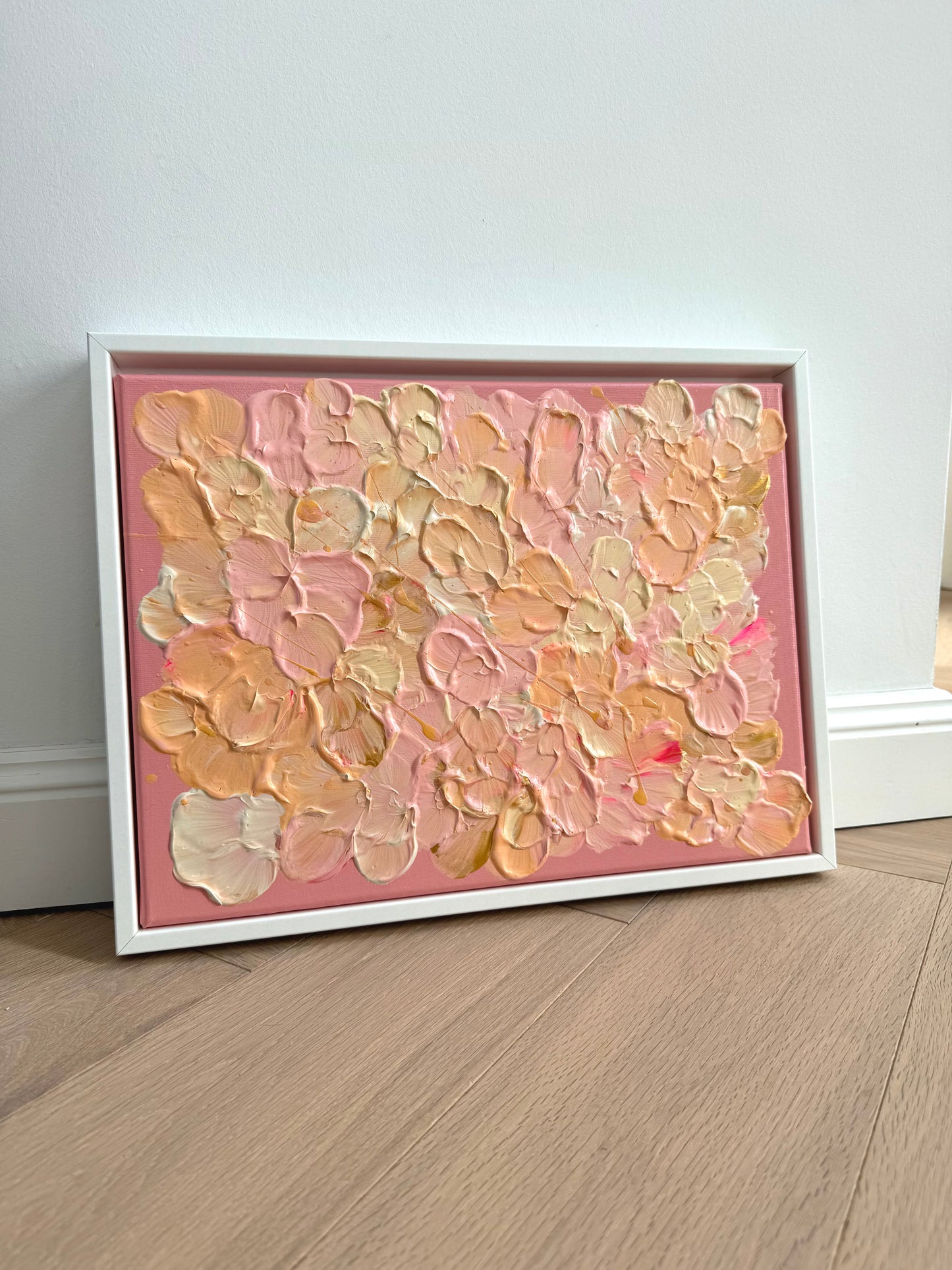 Gerahmtes Acrylbild FLORALS #19 im Querformat, angelehnt an eine helle Wand, mit floraler Textur in Rosa, Apricot und Buttergelb.