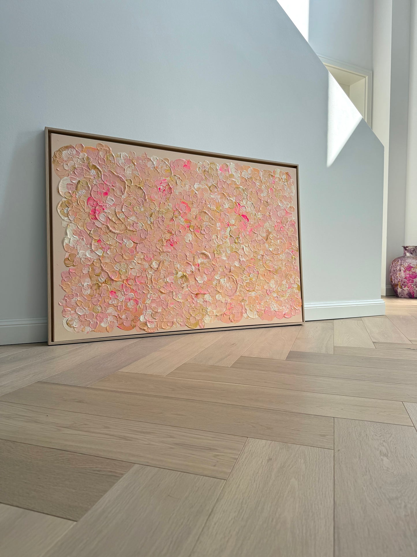 FLORALS #21 schräg aufgestellt vor heller Wand, großes florales Originalkunstwerk in pudrigen Rosa-, Rosé- und Apricottönen im Eichenrahmen.