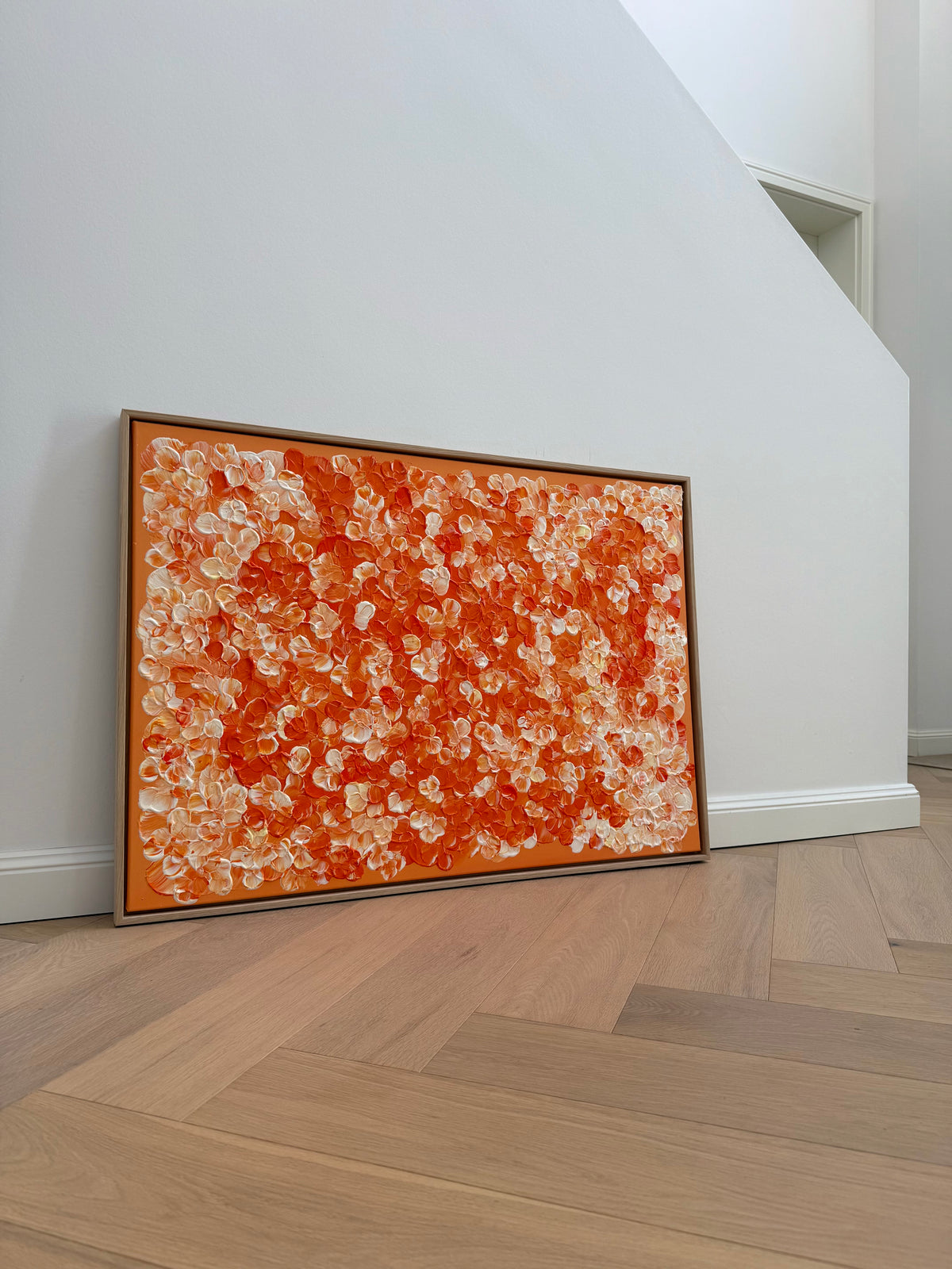 Raumansicht von FLORALS #25 mit abstrakten Blütenformen in verschiedenen Orangetönen, Cremeweiß und zartem Hellgelb auf orangefarbenem Grund.