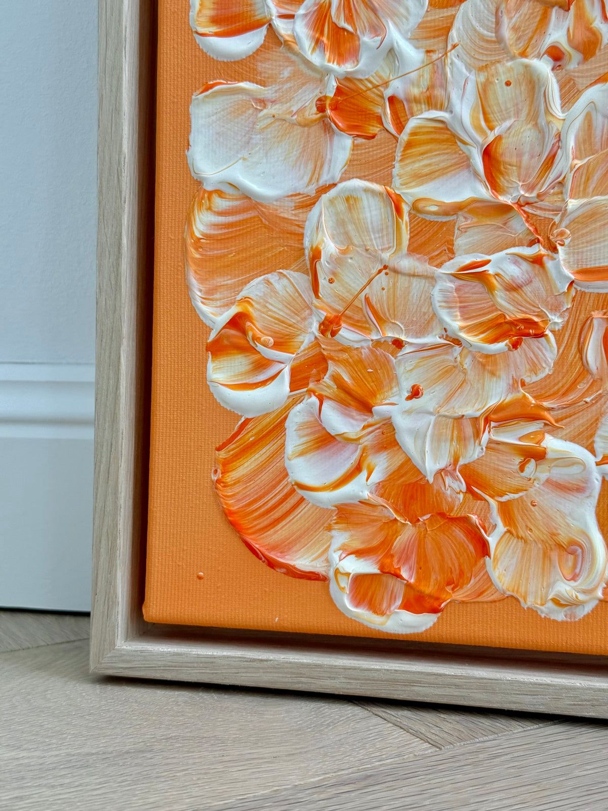 Untere linke Ecke von FLORALS #25 mit erhabenen Blütenrändern, feinen orangefarbenen Sprenkeln und sichtbarem Leinwandgewebe neben dem hellen Eichenrahmen.