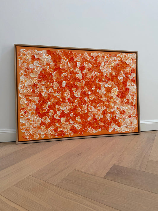 FLORALS #25, florales Acrylbild in saftigen Orangetönen und Cremeweiß, 100 × 70 cm, im hellen Eichenrahmen an eine weiße Wand gelehnt.
