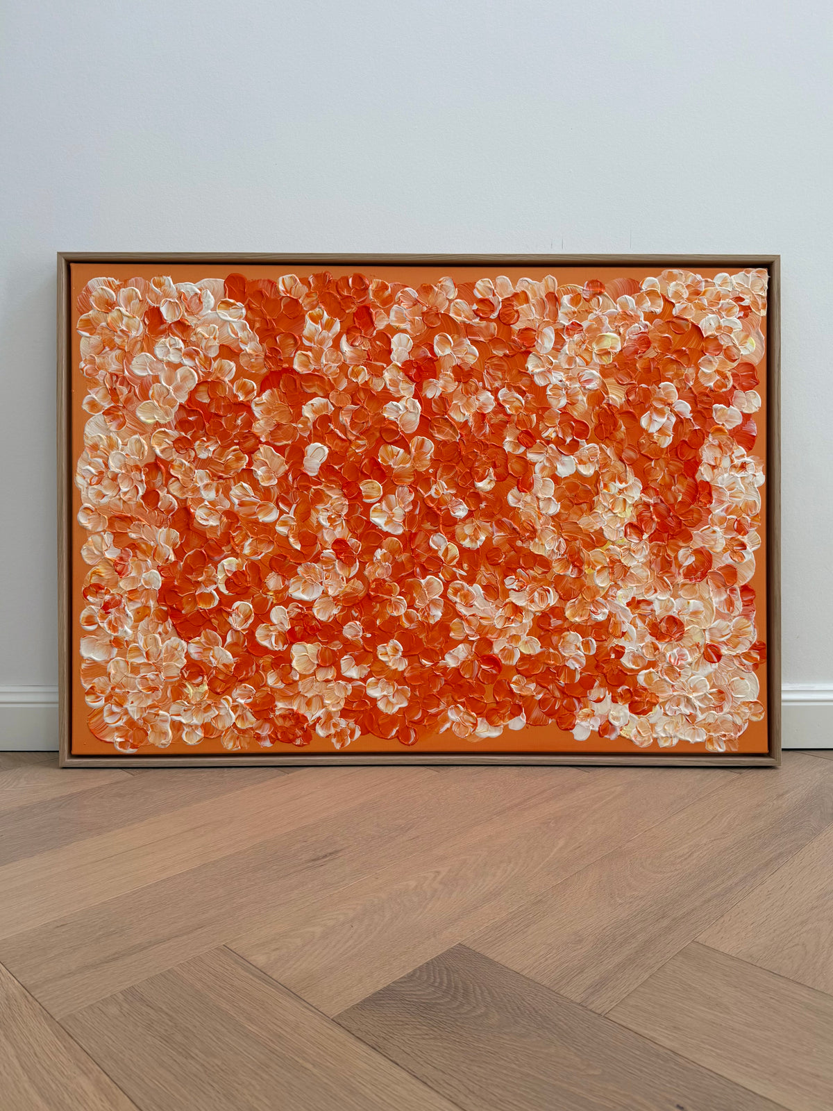 Gesamtansicht von FLORALS #25 mit dicht verteilten orangefarbenen und cremeweißen Blütenformen, präsentiert im Schattenfugenrahmen aus Eiche Natur auf hellem Holzboden.