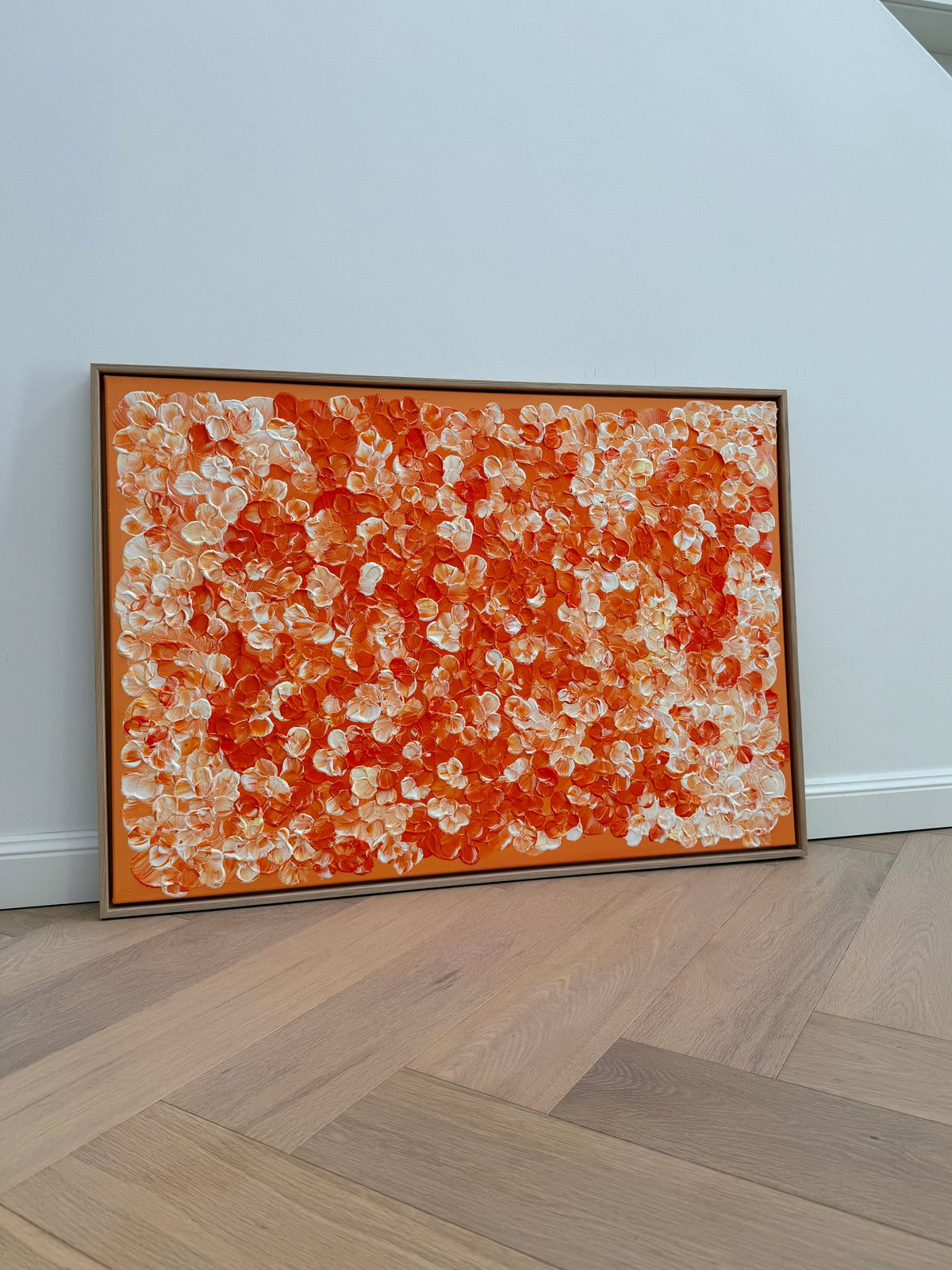 FLORALS #25 aus seitlicher Perspektive im hellen Raum, mit plastischer Blütenkomposition in Orange und Cremeweiß sowie einem Rahmen aus Eiche Natur.