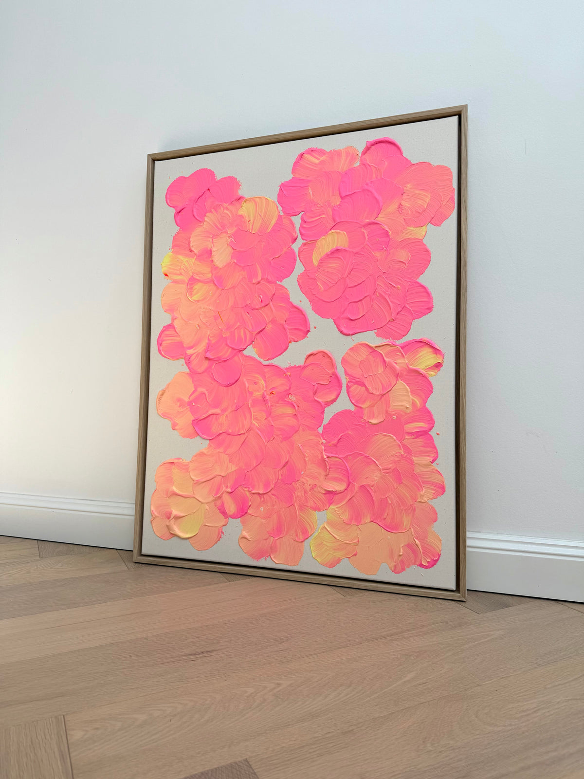 Seitliche Gesamtansicht von FLORALS #27, an eine helle Wand gelehnt, mit großzügigen Blütengruppen in Pink und Lachsorange im naturfarbenen Eichenrahmen.