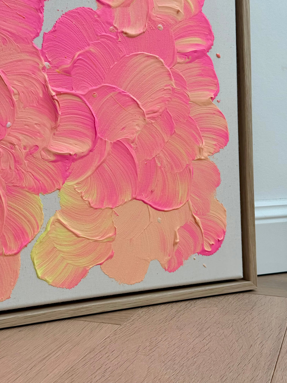 Untere rechte Ecke von FLORALS #27 mit breiten Blütenformen in Pink, Lachsorange und Hellgelb auf roher Leinwand neben dem hellen Holzrahmen.