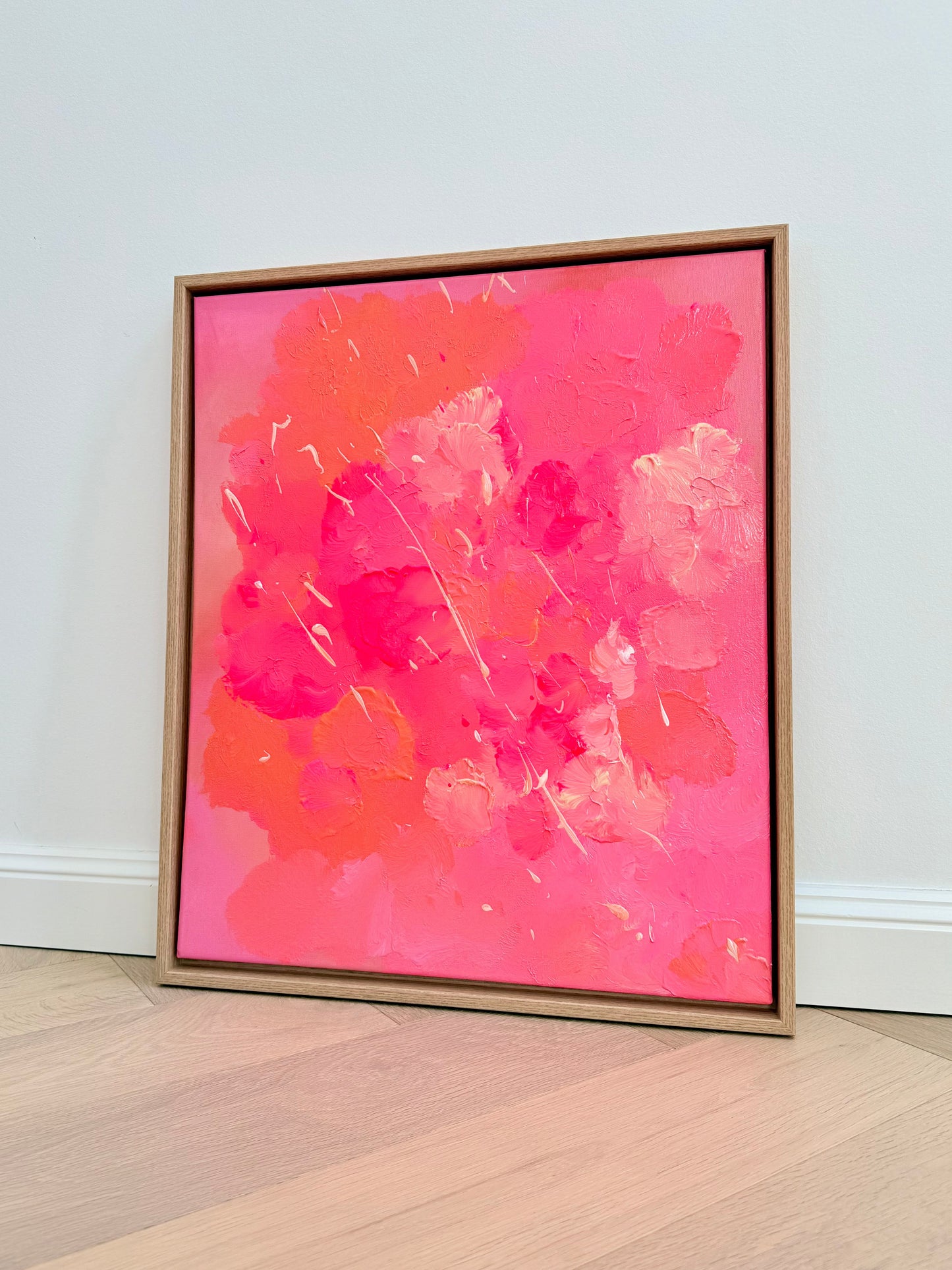 FLORALS #2 – Abstraktes florales Originalkunstwerk in Pink, Rosa, Koralle und Creme mit sichtbarer Textur, gerahmt in Eiche Natur, frontal fotografiert vor heller Wand.