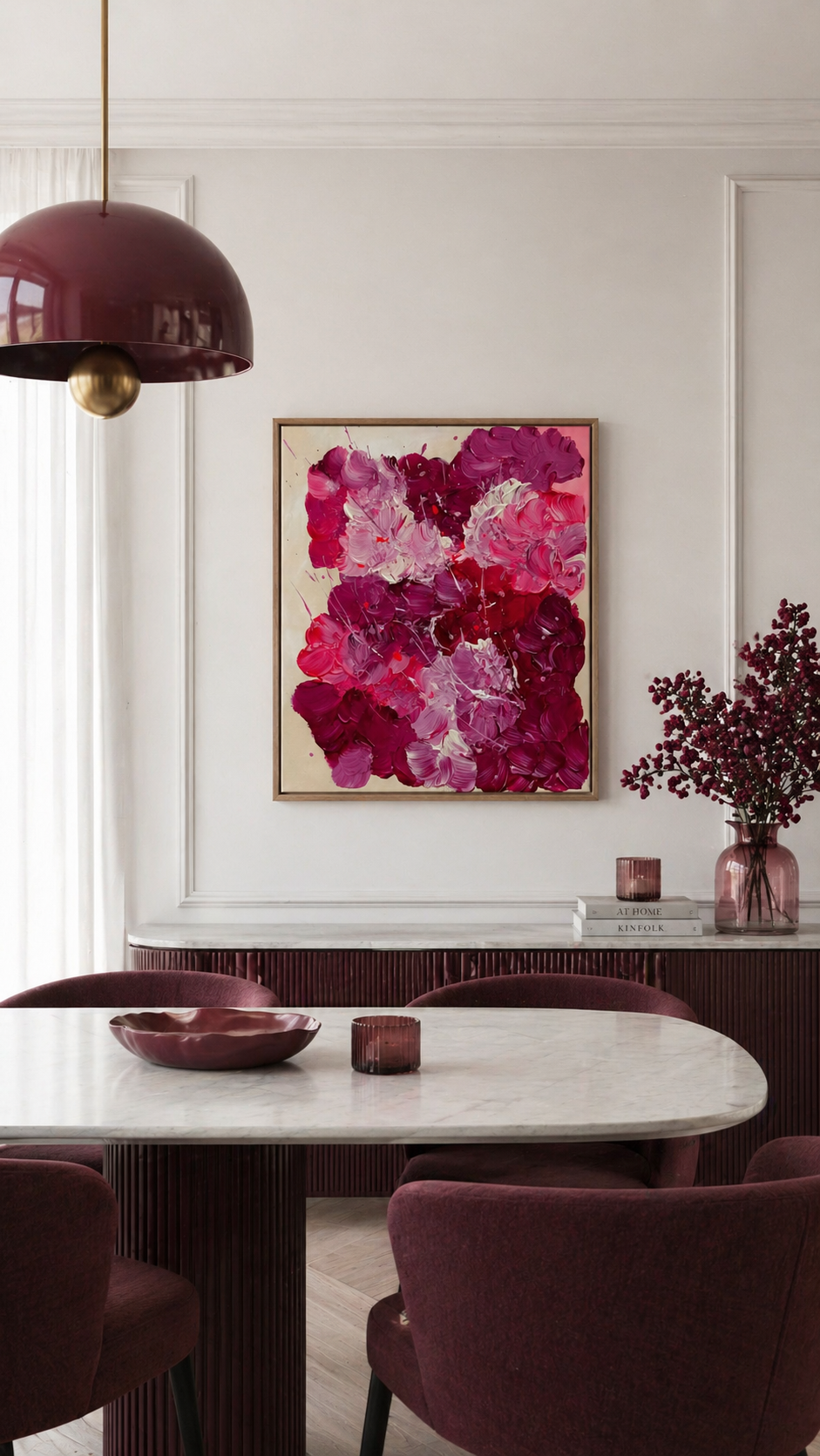 Moderner Essbereich mit hellem Tageslicht, runder Holztisch und beerenfarbene Samtstühle. An einer hellen Wand hängt ein abstraktes Acrylgemälde in Pink-, Rosé- und Beerentönen (50x60 cm) in Holzrahmen. Warme, elegante Interior-Details mit passender Pendelleuchte und floraler Dekoration.