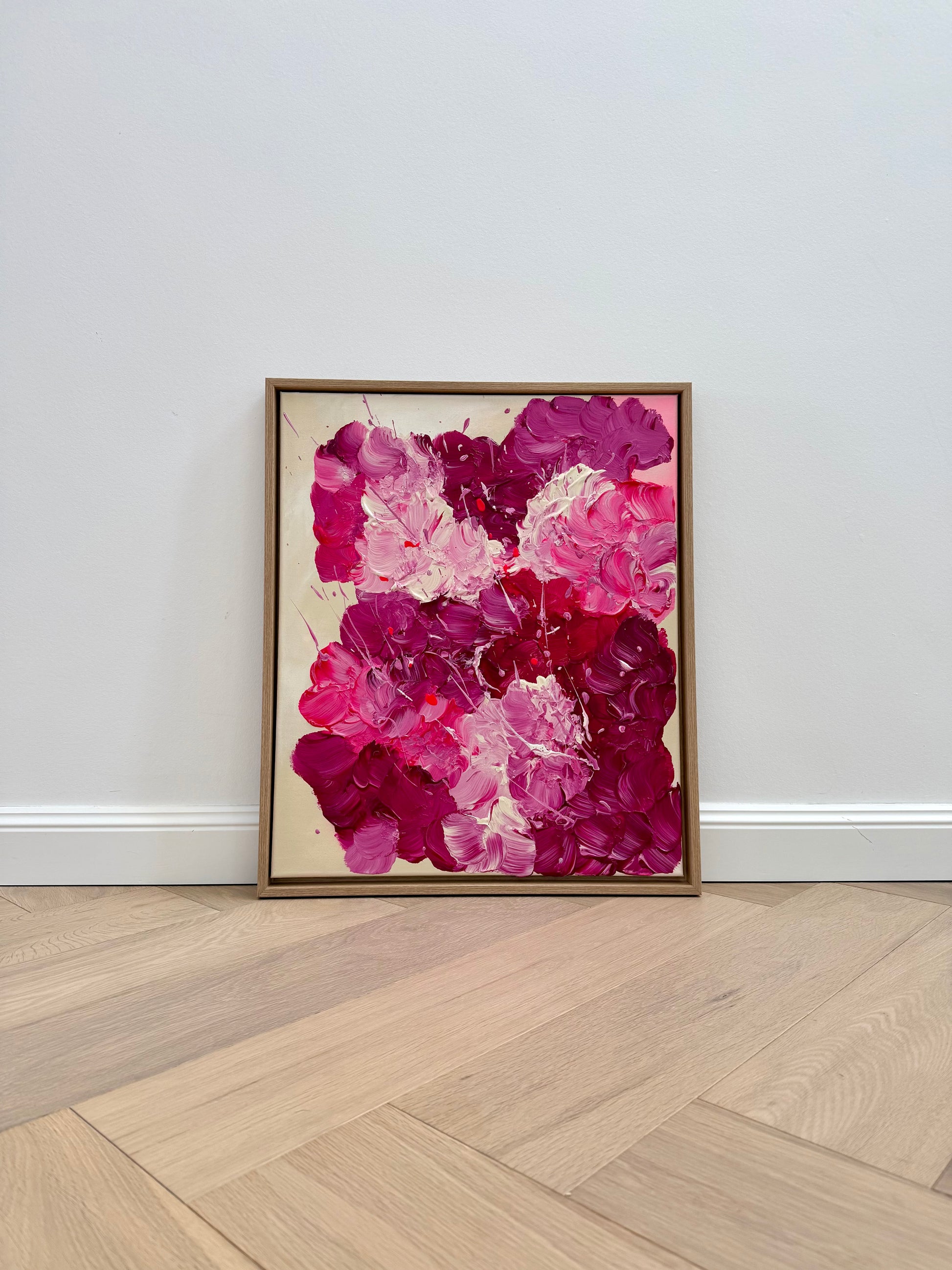 Abstraktes Acrylbild 50x60 cm im Eiche-Rahmen an heller Wand aufgestellt. Strukturreiche florale Wandkunst in Pink und Rosé für moderne Wohnräume.