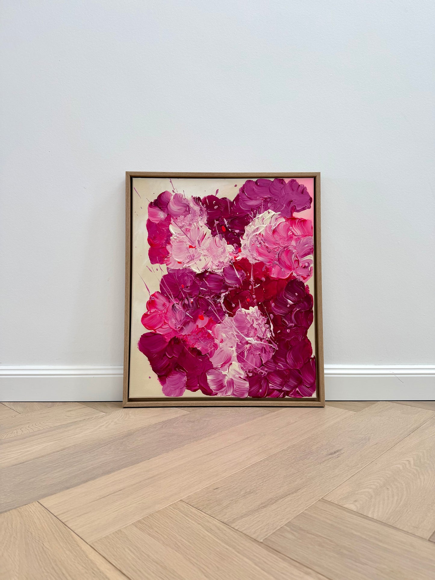 Abstraktes Acrylbild „FLORALS #3“ in Pink und Burgunder im Eiche-Schattenfugenrahmen, auf dem Boden an eine helle Wand gelehnt. Moderne florale Wandkunst mit strukturreicher Oberfläche und glänzendem Finish, ideal für minimalistisches Interior.