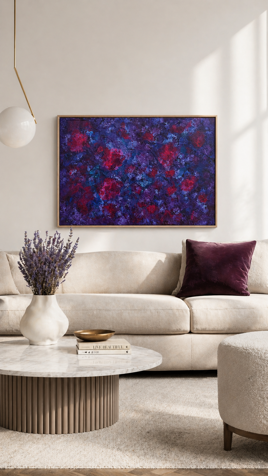 Modernes, helles Wohnzimmer im Scandi-Stil mit beigefarbenem Sofa, rundem Marmortisch und minimalistischer Pendelleuchte. An der hellen Wand hängt ein großes abstraktes Acrylbild (ca. 70x50 cm) in tiefen Lila-, Blau- und Magentatönen mit strukturierter Textur und floraler Anmutung, harmonisch abgestimmt auf das Interior und beleuchtet von natürlichem Tageslicht.