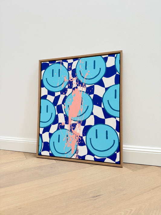 Abstraktes Acrylbild HAPPY #13 mit hellblauen Smileys, blau-weißem Schachbrettmuster und apricotfarbenen Farbspritzern, 50x60 cm, gerahmt in Eiche.