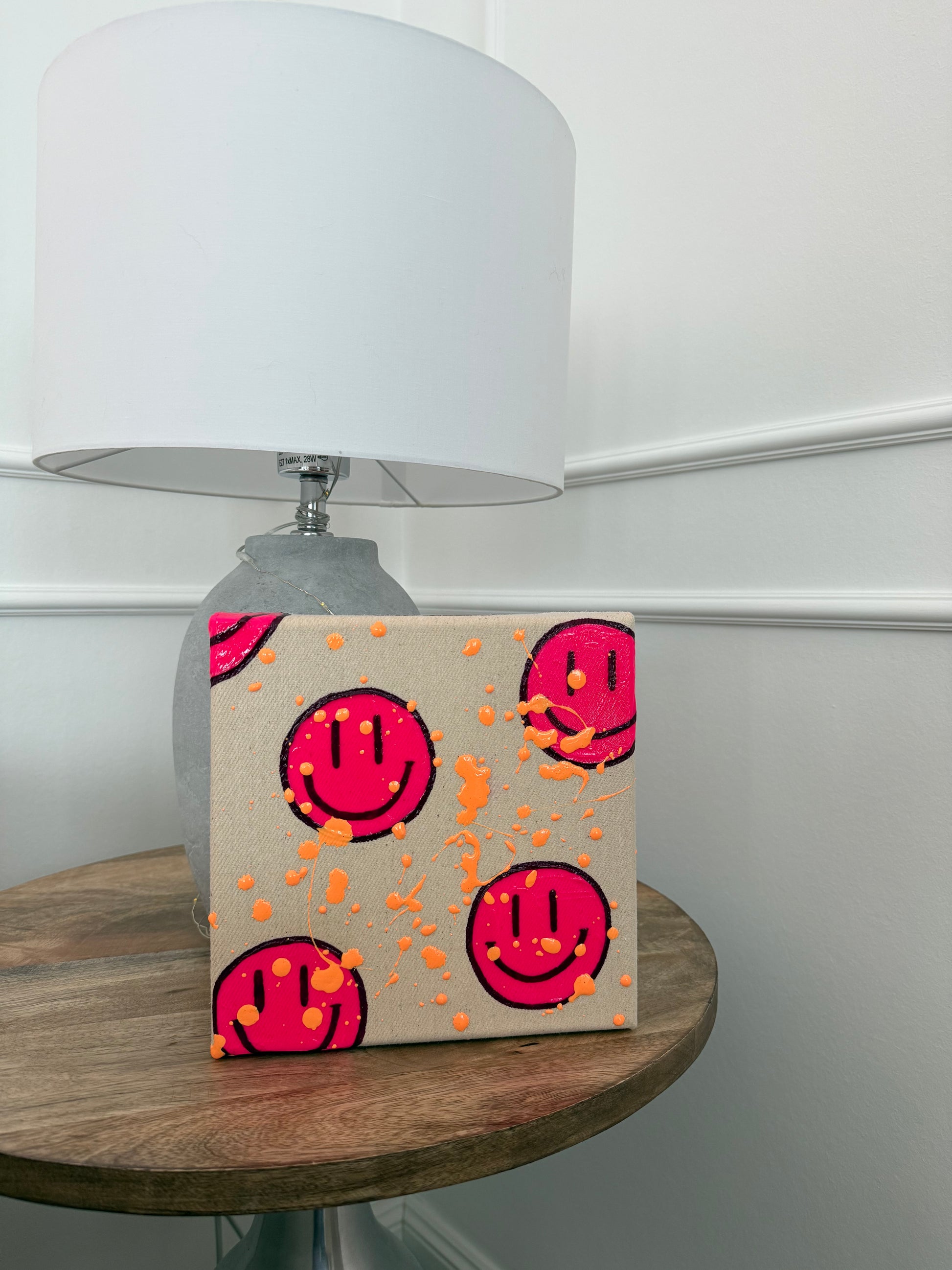 Interior Szene mit Smiley Kunstwerk „HAPPY #14“ auf Tisch – modernes Acrylbild in Neonpink als Dopamine Decor Wandkunst