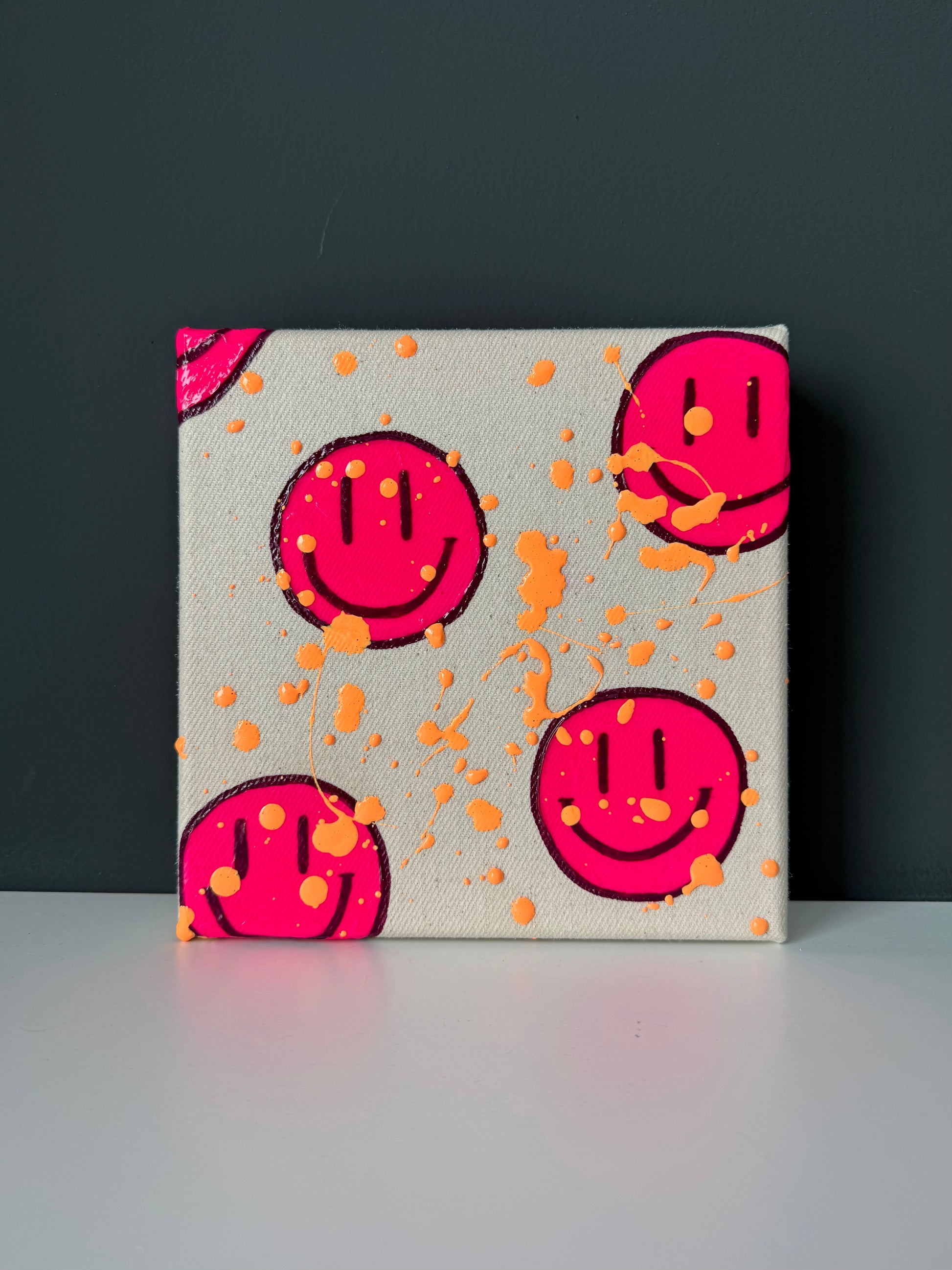 Modernes Smiley Kunstwerk in Neonpink auf dunklem Hintergrund – kleines Acrylbild aus der HAPPY Serie als farbige Wandkunst
