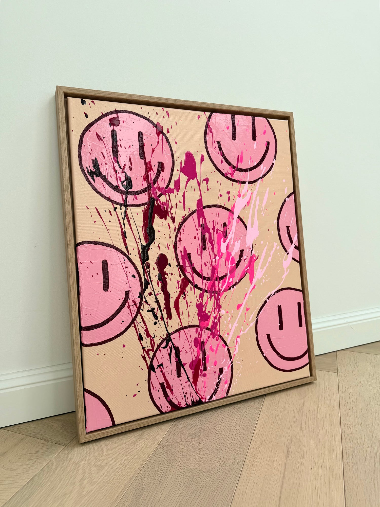Abstraktes Acrylgemälde mit pinken Happy-Face-Motiven und dynamischen Farbspritzern in Neonpink, Bordeaux und Dunkelrot auf beigem Hintergrund, moderner Holzrahmen, zeitgenössische Wandkunst