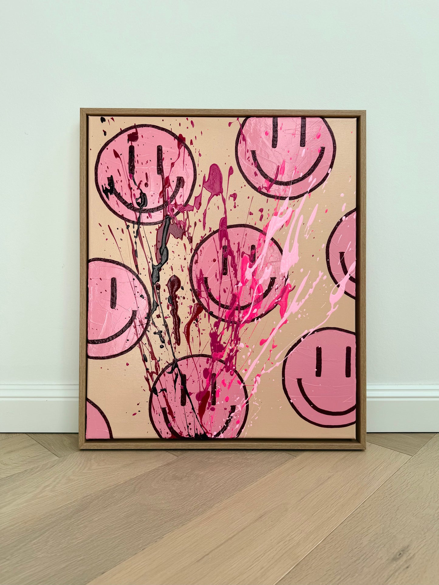 Aufnahme eines abstrakten Happy-Face Gemäldes mit sichtbarer Textur, Schichten und Farbspritzern in Neonpink, Rosa und Bordeaux auf beigem Hintergrund, moderne Acrylkunst