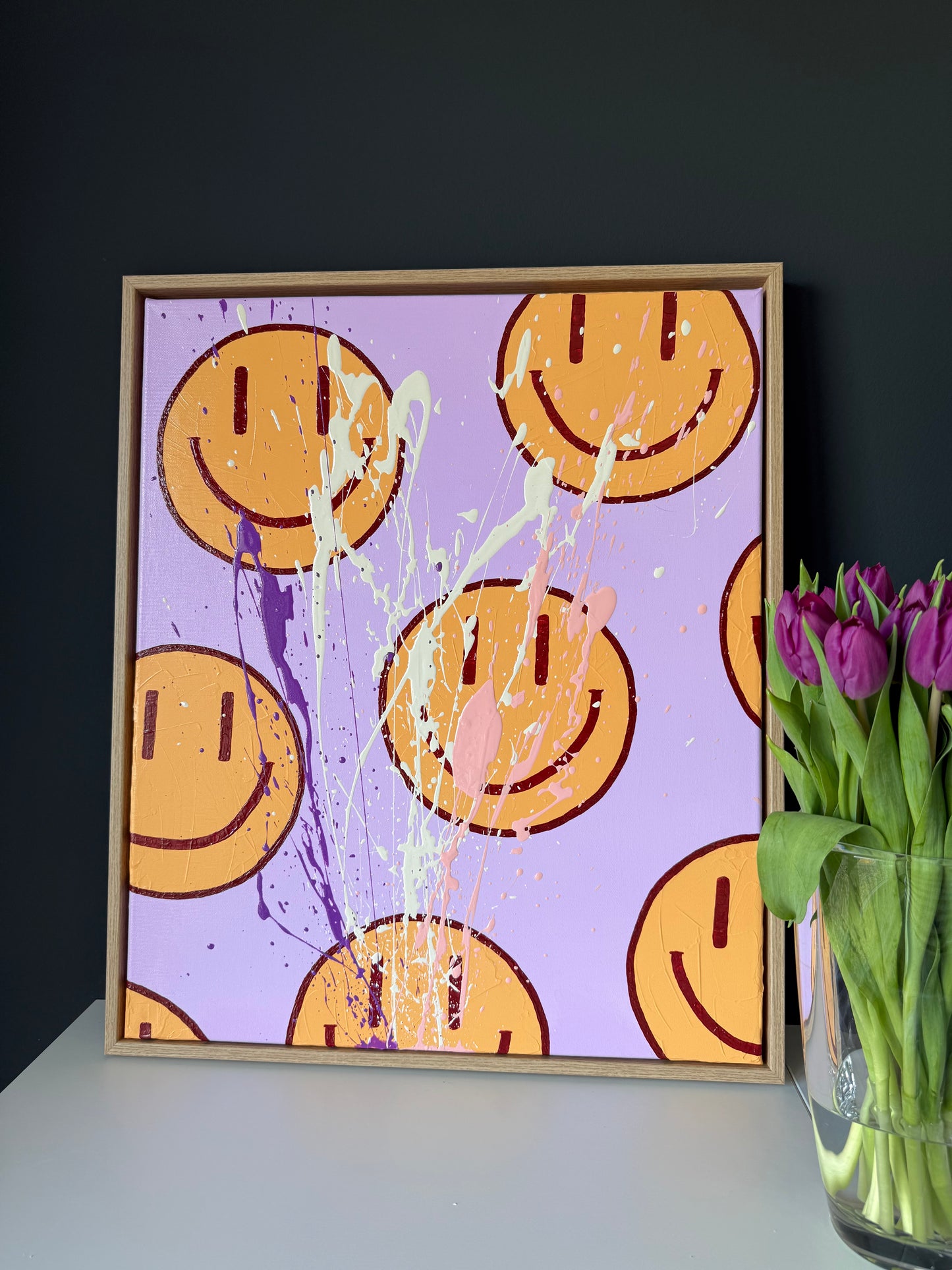 HAPPY #16 als Happy Face Wandbild in minimalistischem Interior, abstrakte Kunst in Flieder und Orange mit glänzendem Finish.