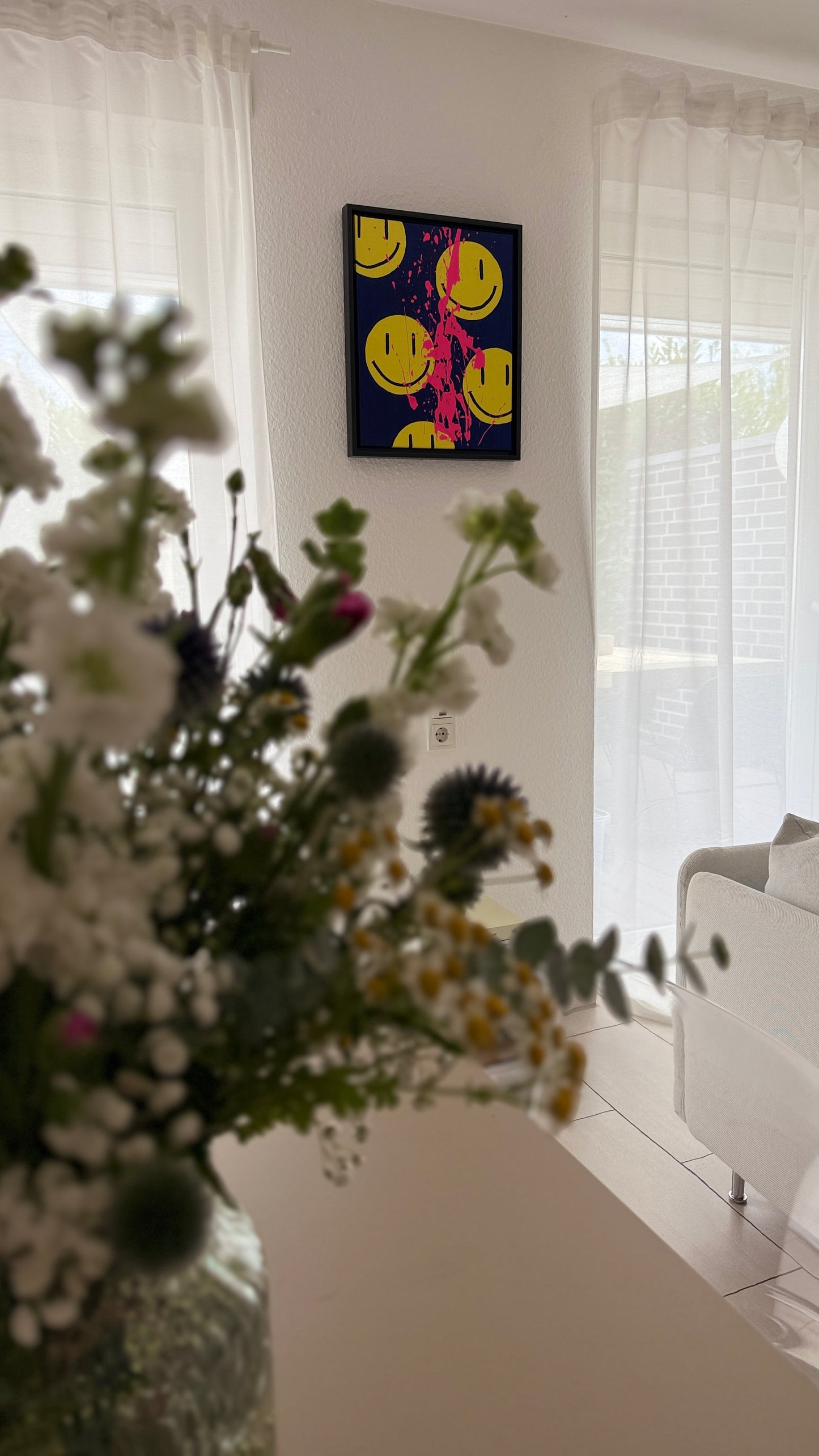 Kunstwerk im Interior (Wohnzimmer): Gelbe Smileys auf dunkelblauen Hintergrund mit neonpinken Farbspritzern