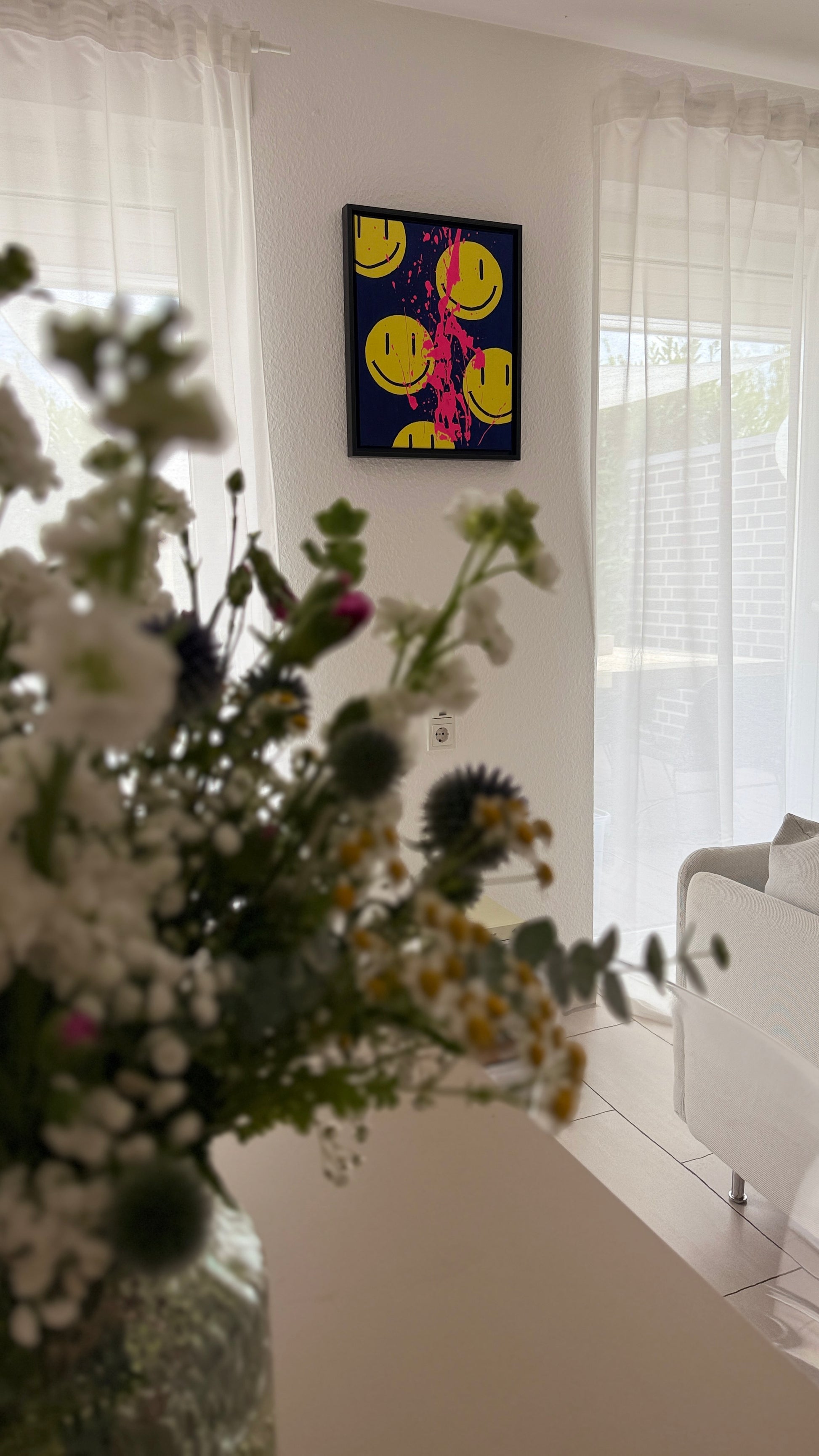 Kunstwerk im Interior (Wohnzimmer): Gelbe Smileys auf dunkelblauen Hintergrund mit neonpinken Farbspritzern