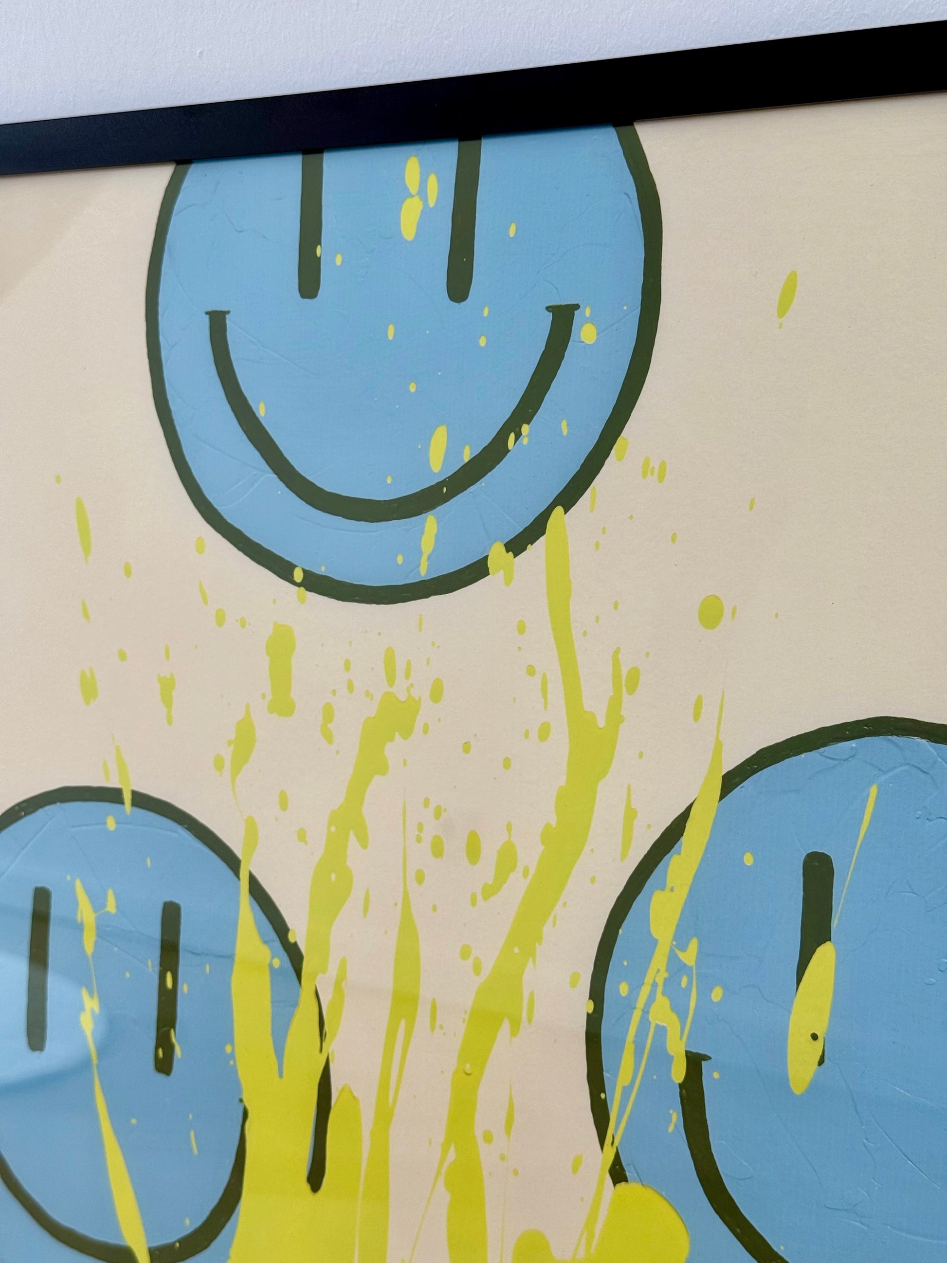Detailaufnahme der oberen Bildhälfte von HAPPY #21 mit einem großen hellblauen Happy-Face, olivfarbener Kontur und gelben Farbsprenkeln.