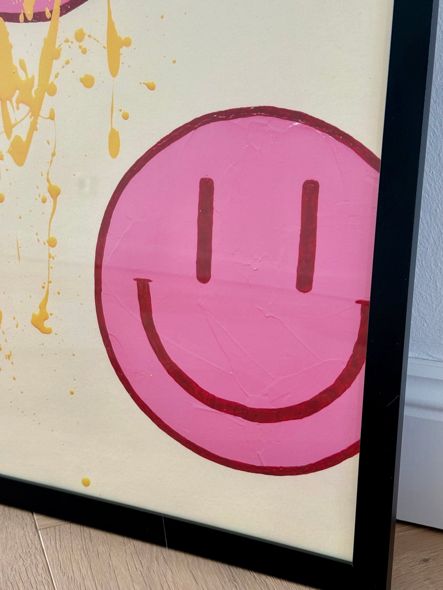 Seitliche Nahaufnahme eines großen pinkfarbenen Happy-Faces mit bordeauxroter Kontur auf dem cremefarbenen Hintergrund von HAPPY #22.