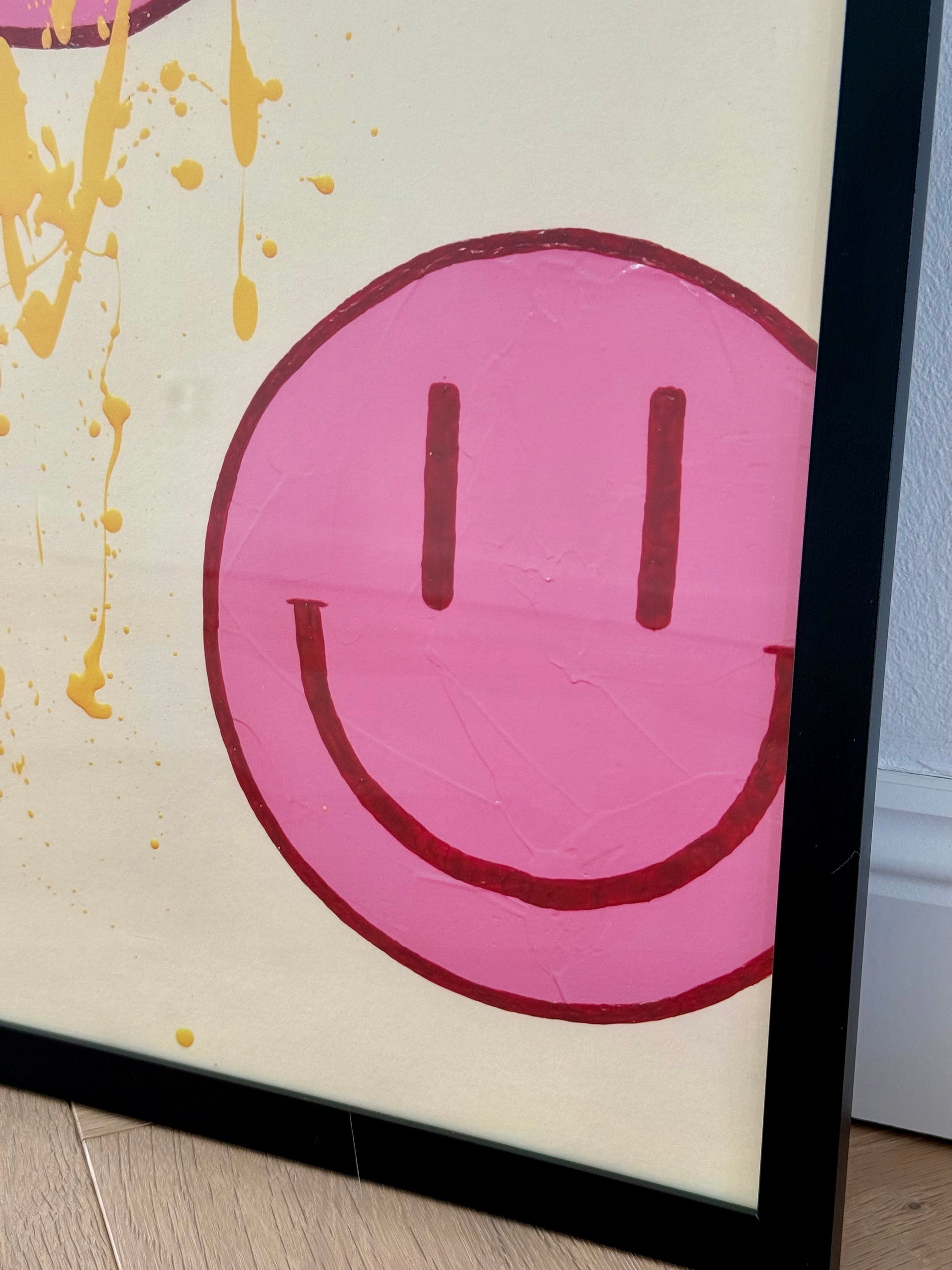 Seitliche Nahaufnahme eines großen pinkfarbenen Happy-Faces mit bordeauxroter Kontur auf dem cremefarbenen Hintergrund von HAPPY #22.