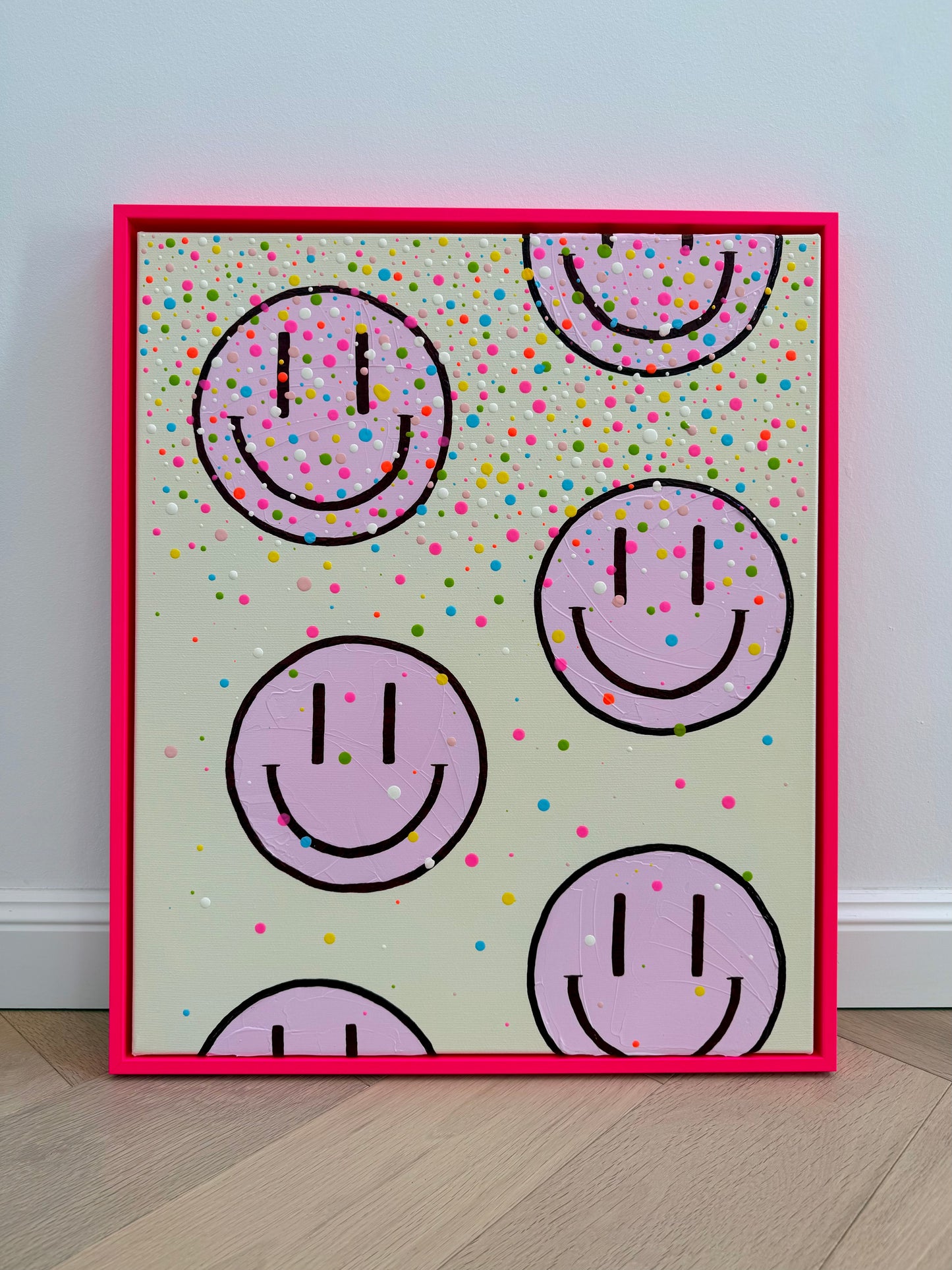 Frontalansicht von HAPPY #26, einem abstrakten Acrylbild mit hellrosa Happy Faces, hellbeigem Hintergrund und neonpinkem Schattenfugenrahmen.