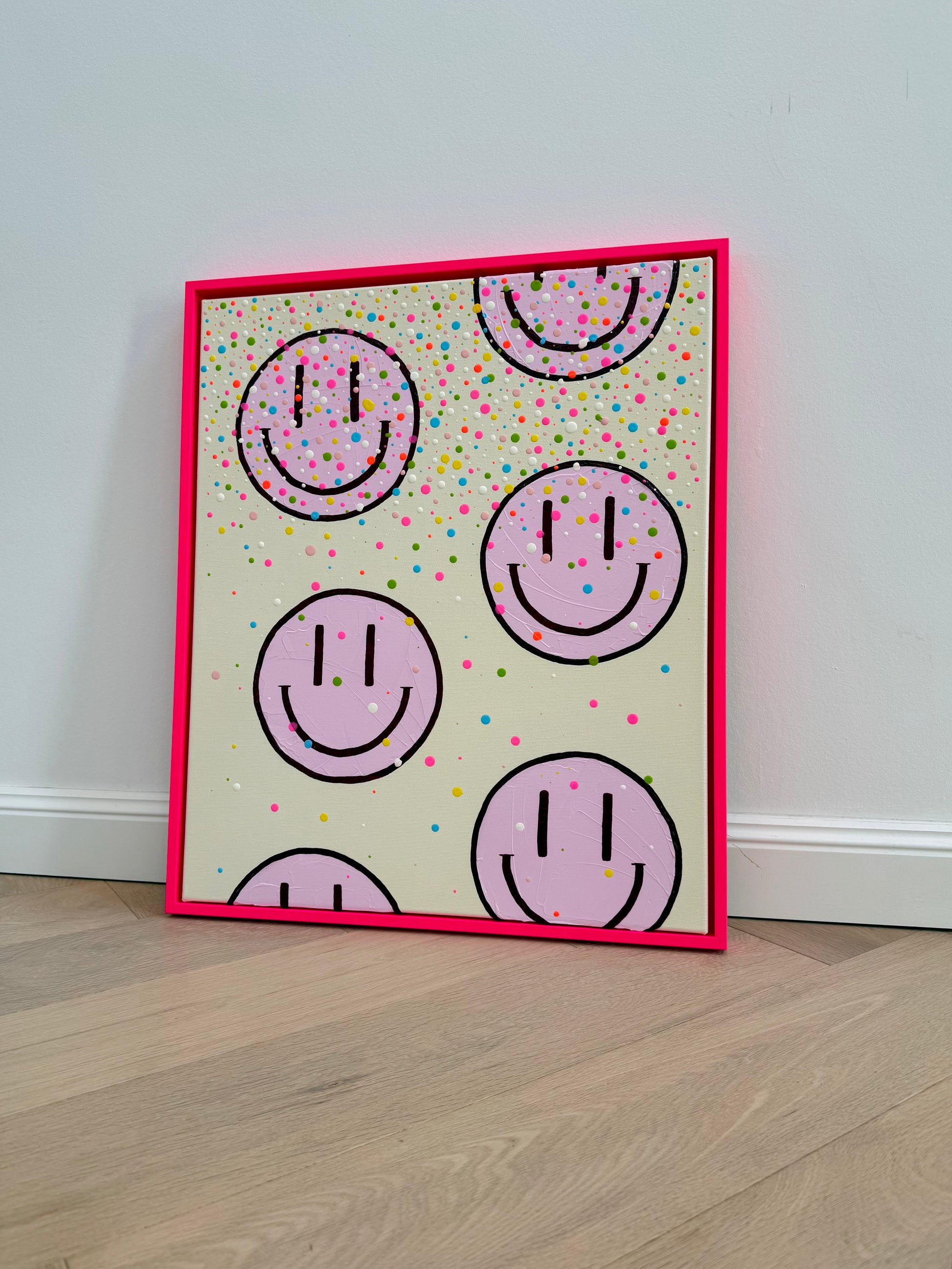 Gesamtansicht des modernen Acrylbildes HAPPY #26 mit hellrosa Happy Faces und bunten Farbakzenten im Schattenfugenrahmen in Neonpink.