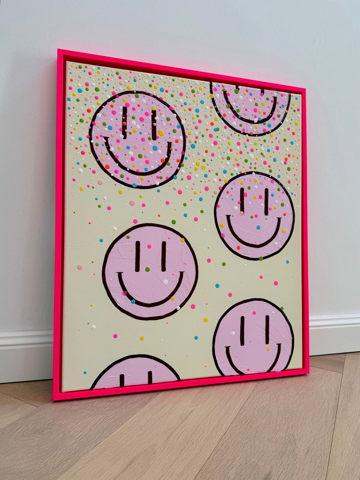 Vollansicht des handgemalten Acrylbildes HAPPY #26 mit hellrosa Happy Faces und bunten Farbtropfen im neonpinken Schattenfugenrahmen.