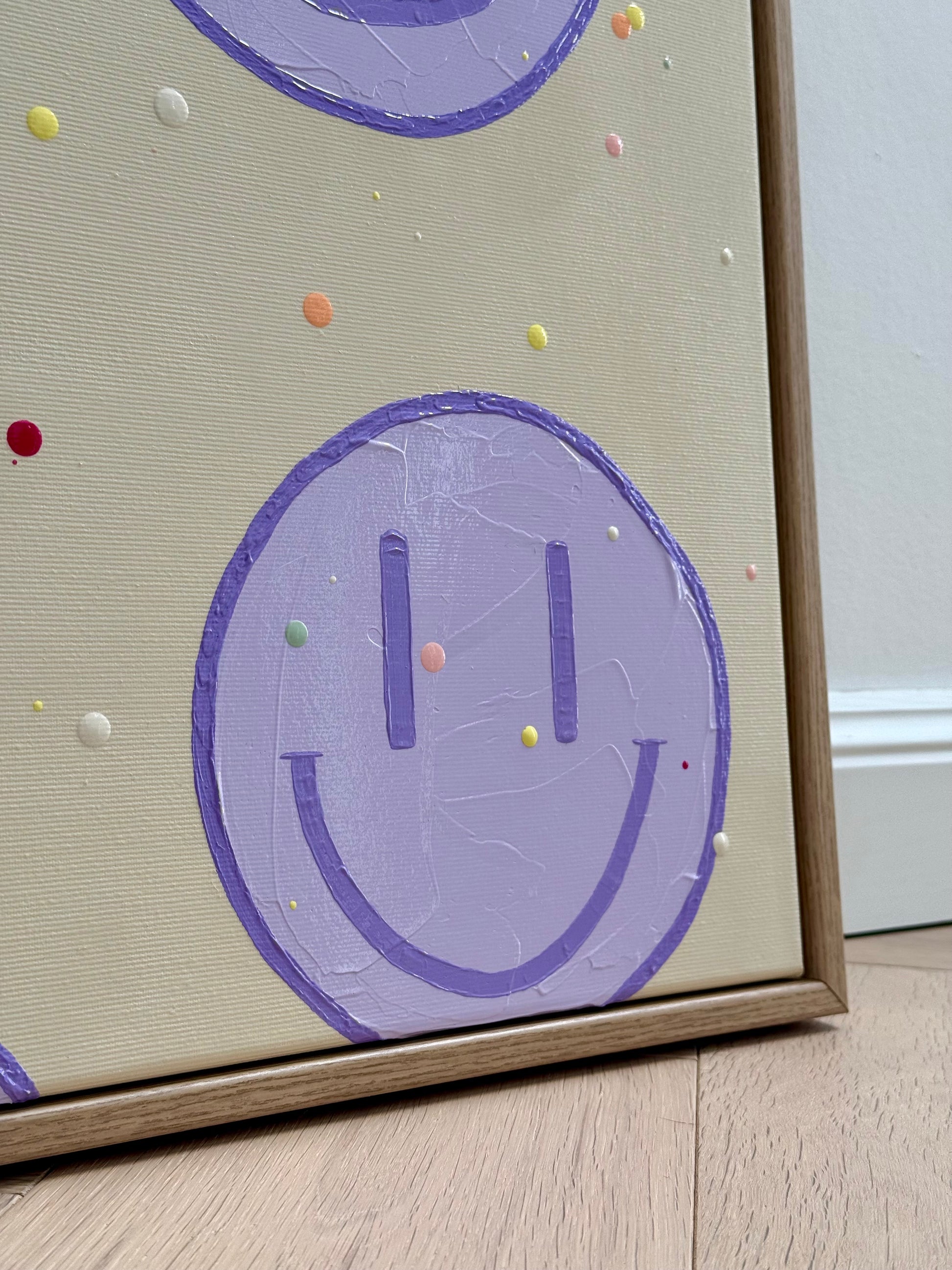Nahaufnahme eines fliederfarbenen Happy-Faces im unteren Bildbereich von HAPPY #27 mit sichtbarer Gel-Medium-Struktur und Eichenrahmen.