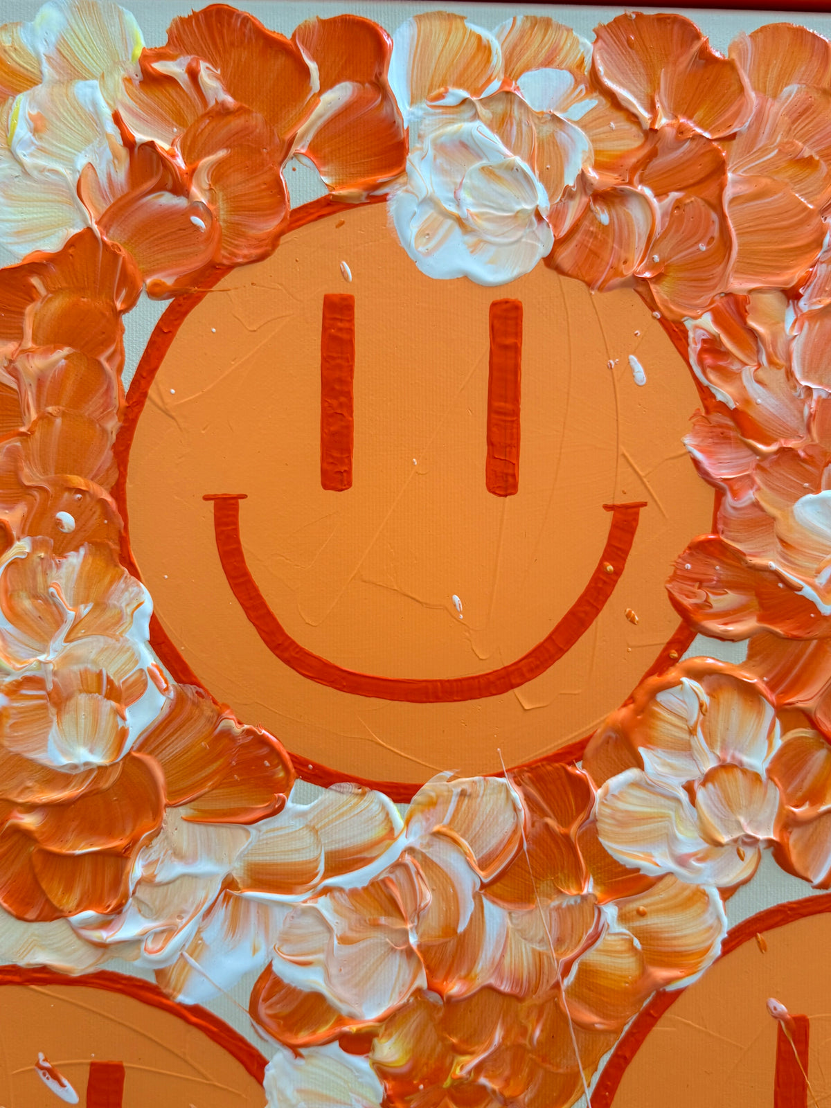 Nahaufnahme eines pastellorangefarbenen Happy Face in HAPPY #30 mit feinen Farbspuren, umgeben von plastischen Blüten in leuchtendem Orange und Creme.