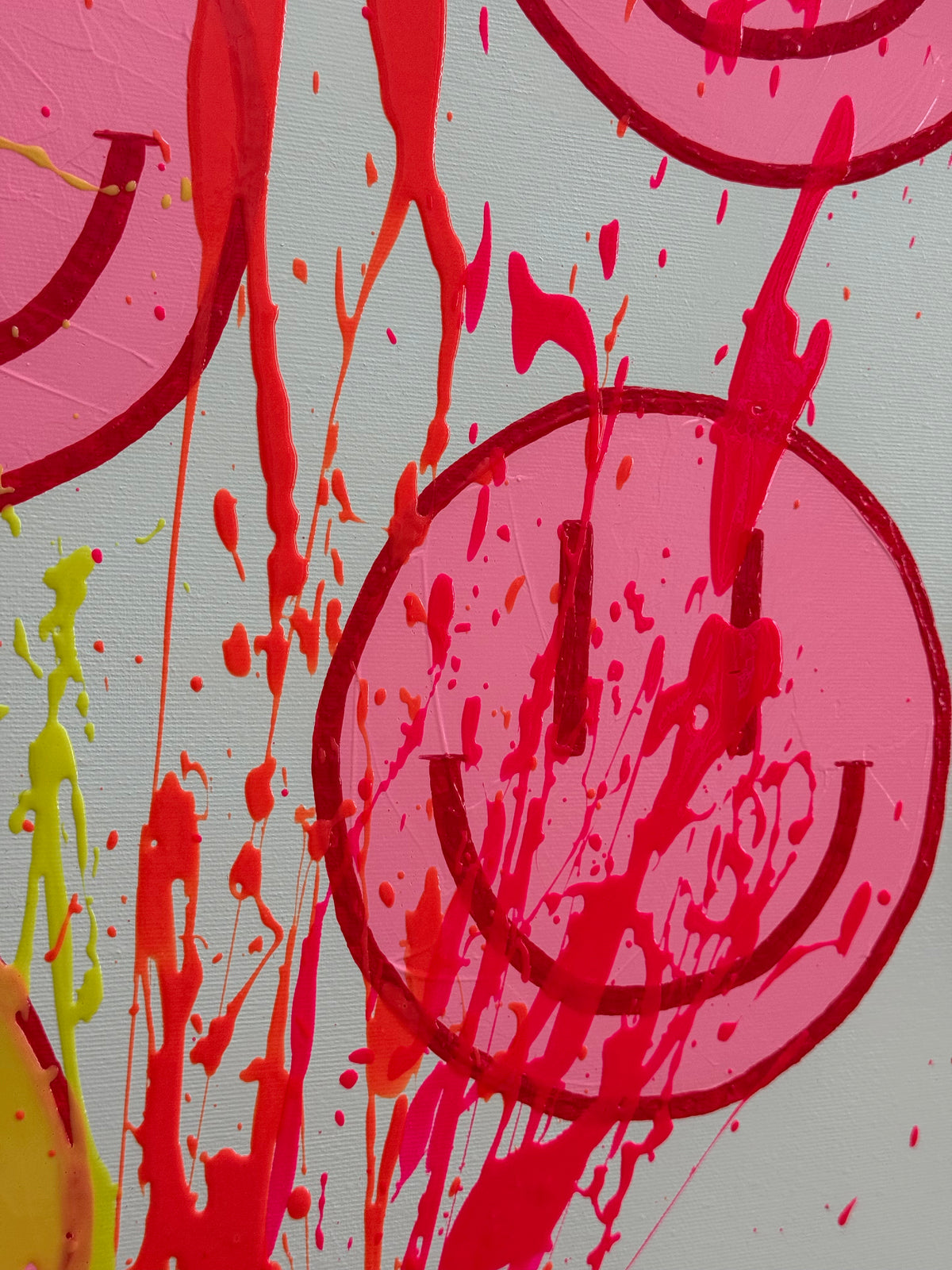 Detail von HAPPY #32 mit neonpinken und neonorangefarbenen Spritzern über einem pinken Happy Face, sichtbaren Erhebungen und feiner Leinwandstruktur.