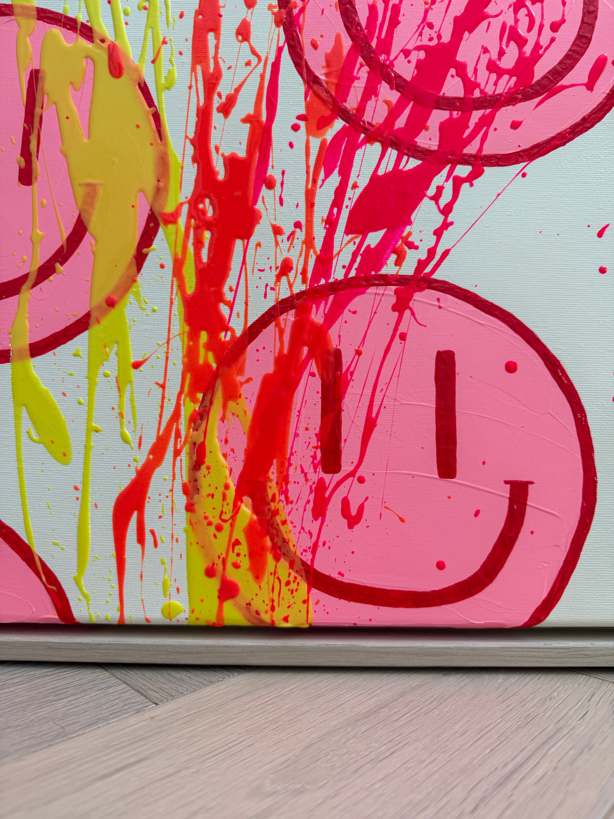 Unterer Bildbereich von HAPPY #32 mit erhabenen Farbspuren in Zitronengelb, Neonorange und Neonpink über pinken Happy Faces, oberhalb des Eichenrahmens.