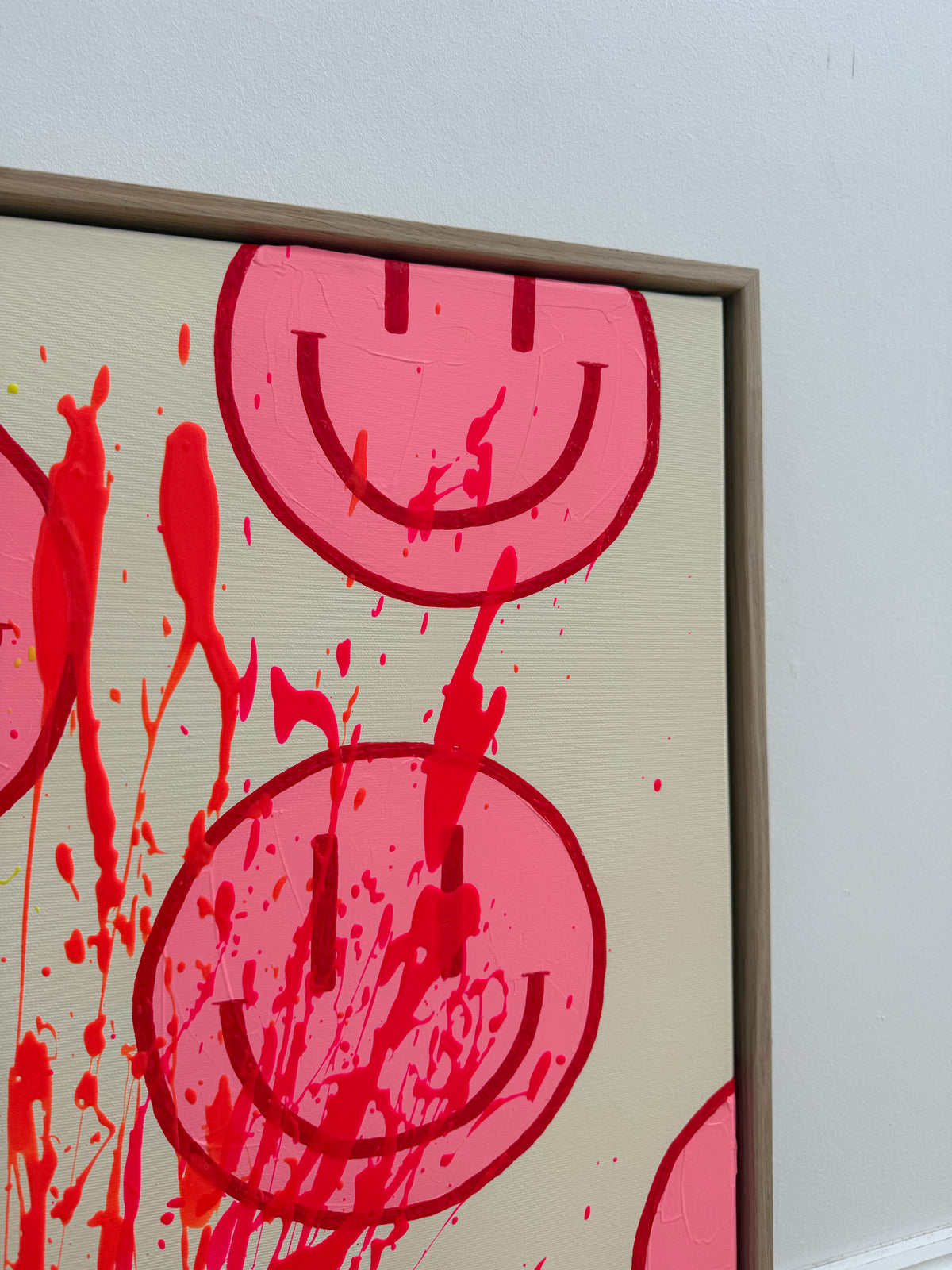 Obere rechte Bildpartie von HAPPY #32 mit angeschnittenem pinkem Happy Face, kirschroten Linien und neonpinken Farbspuren neben dem hellen Eichenrahmen.
