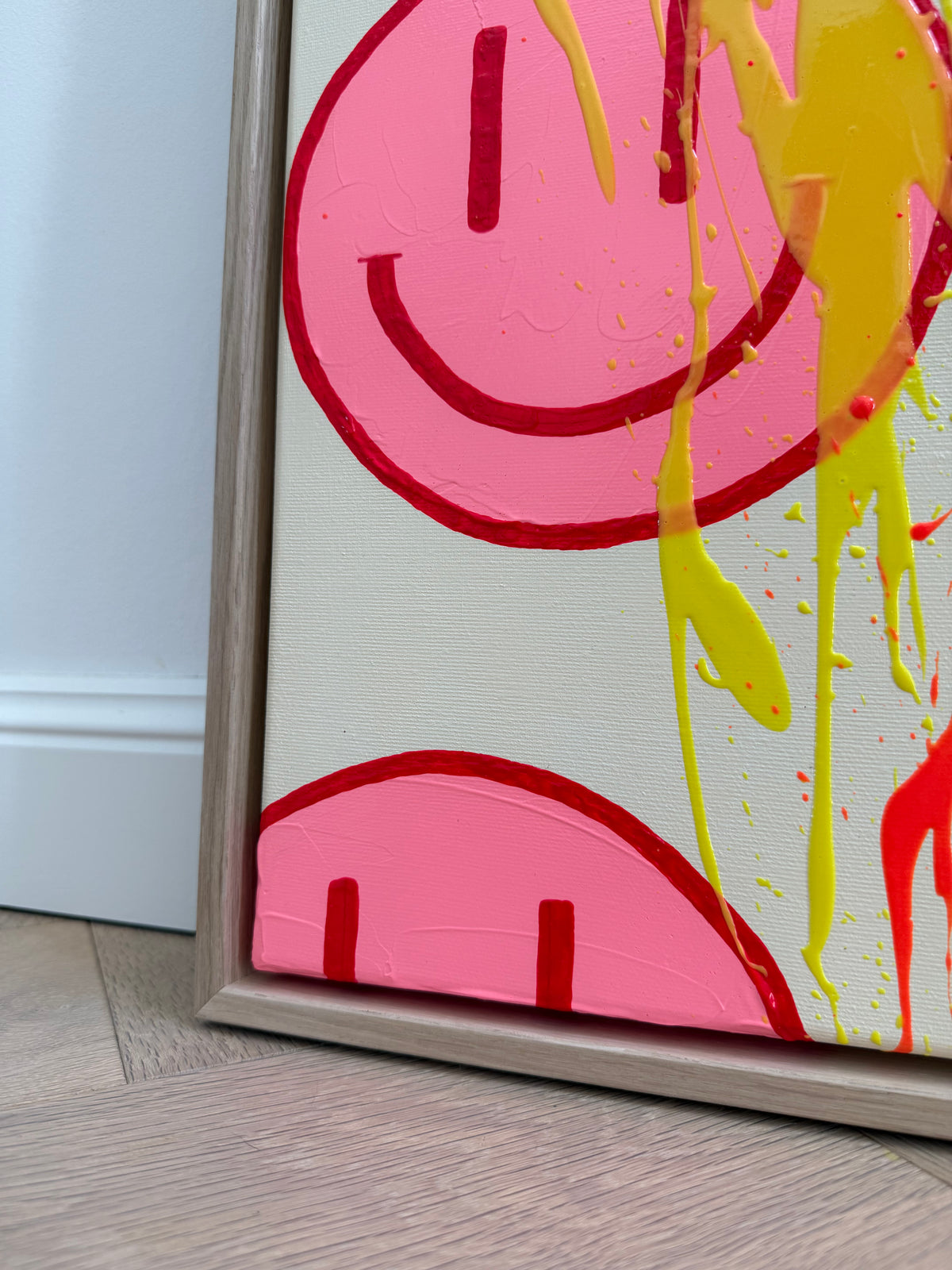 Untere linke Ecke von HAPPY #32 mit angeschnittenen pinken Happy Faces, langgezogenen gelben Farbspuren und Schattenfugenrahmen aus heller Eiche Natur.