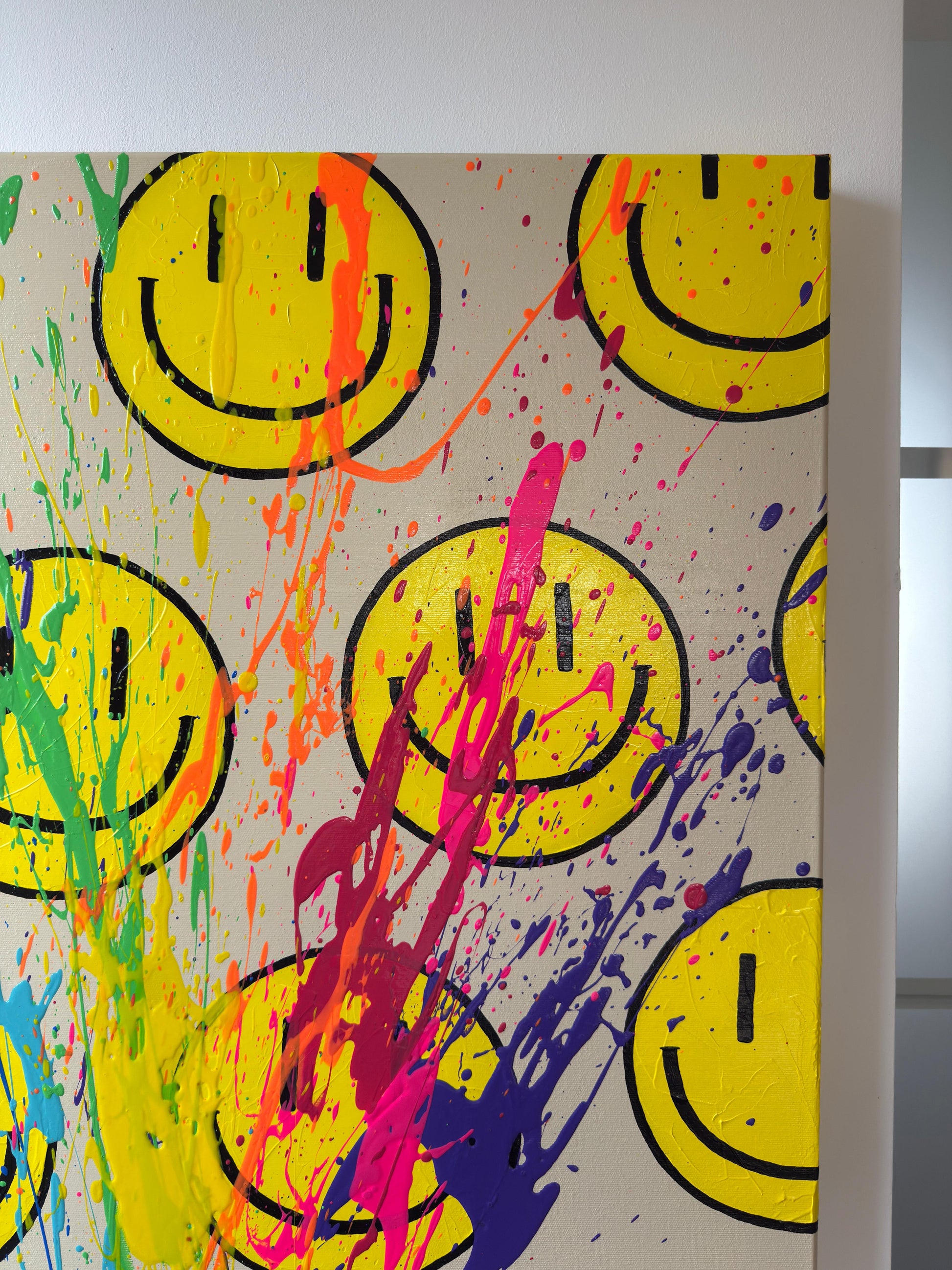 Detailaufnahme abstraktes Happy-Face Kunstwerk mit intensiven pinken und violetten Farbspritzern und sichtbarer Textur auf Leinwand