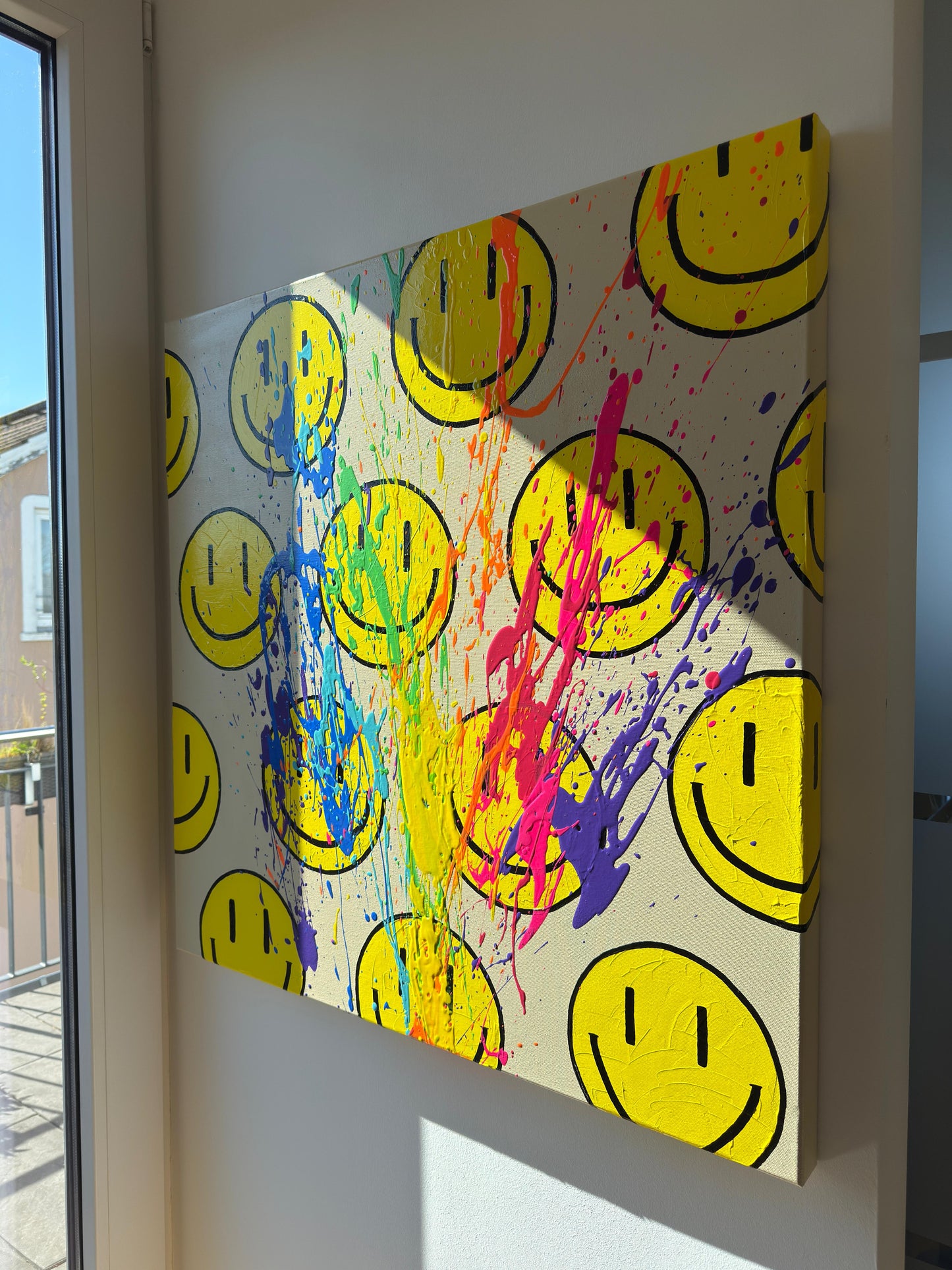 Happy-Faces auf beiger Leinwand mit Farbspritzern in Regenbogenfarben