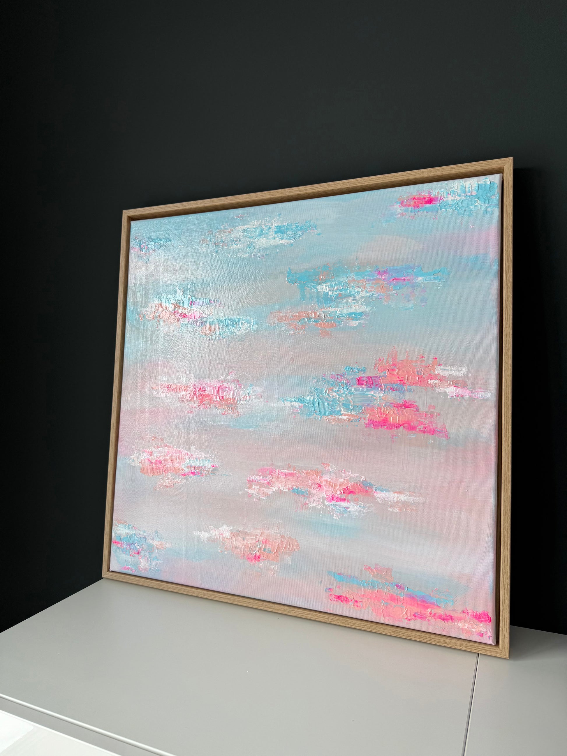 Moderne Wandkunst 60x60 cm in Pastelltönen Blau und Rosé mit sichtbarer Textur und Holzrahmen, seitliche Perspektive