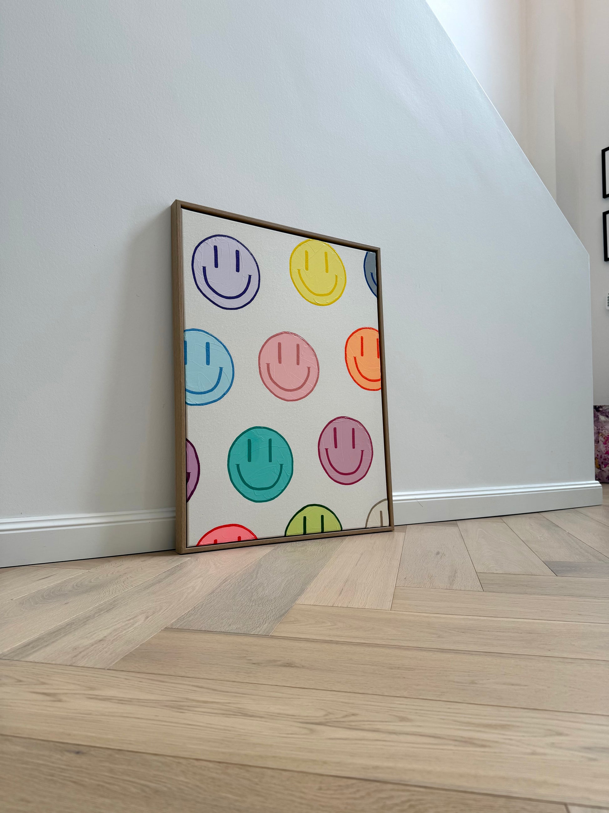 Raumansicht von HAPPY #19 mit pastellfarbenen Happy-Faces, strukturierter Acrylmalerei und hochwertigem Schattenfugenrahmen.