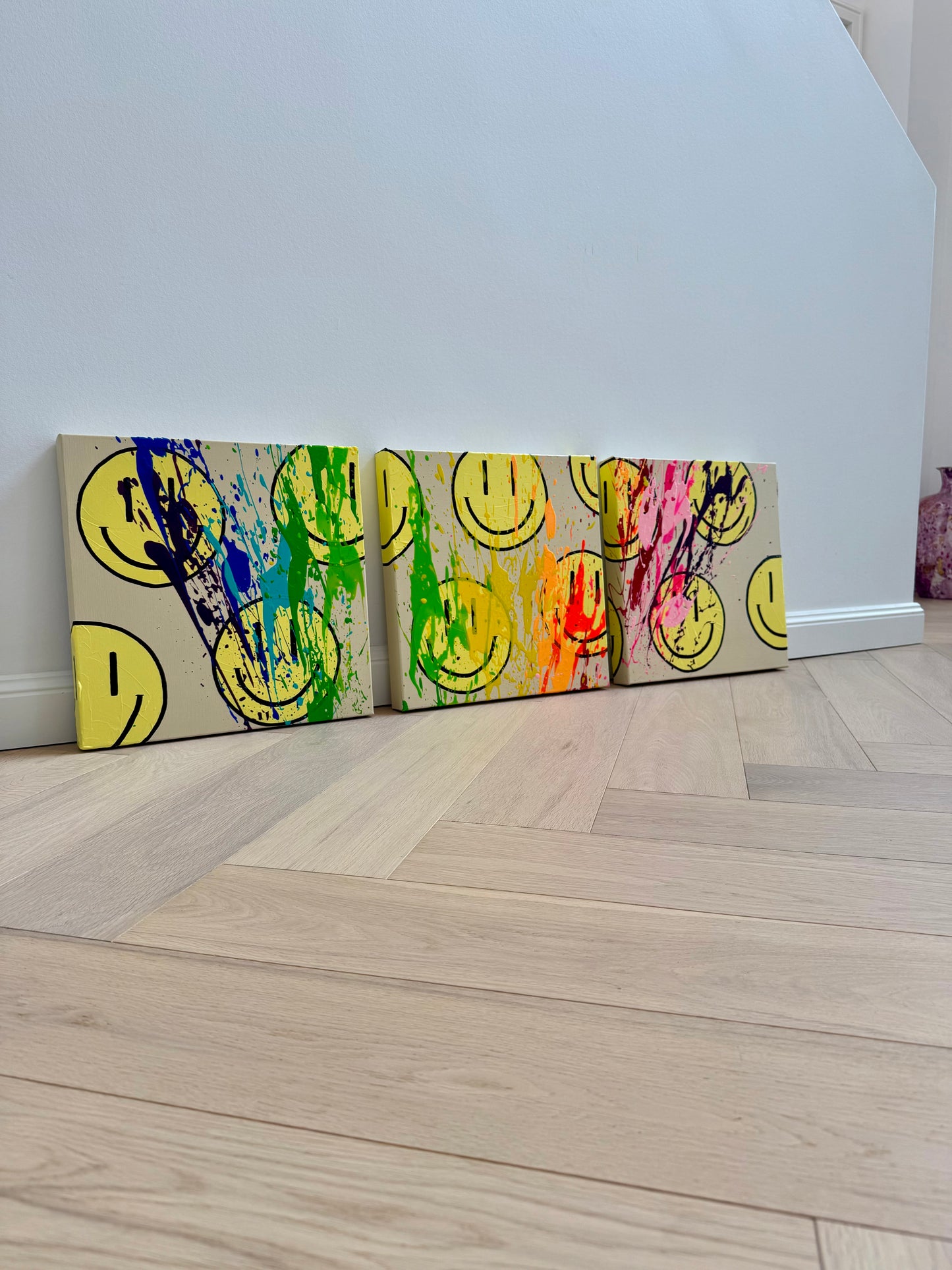 Farbstarkes Triptychon der HAPPY-Serie mit gelben Happy-Faces, Neonfarben und dynamischen Farbspritzern als moderne Wandkunst.