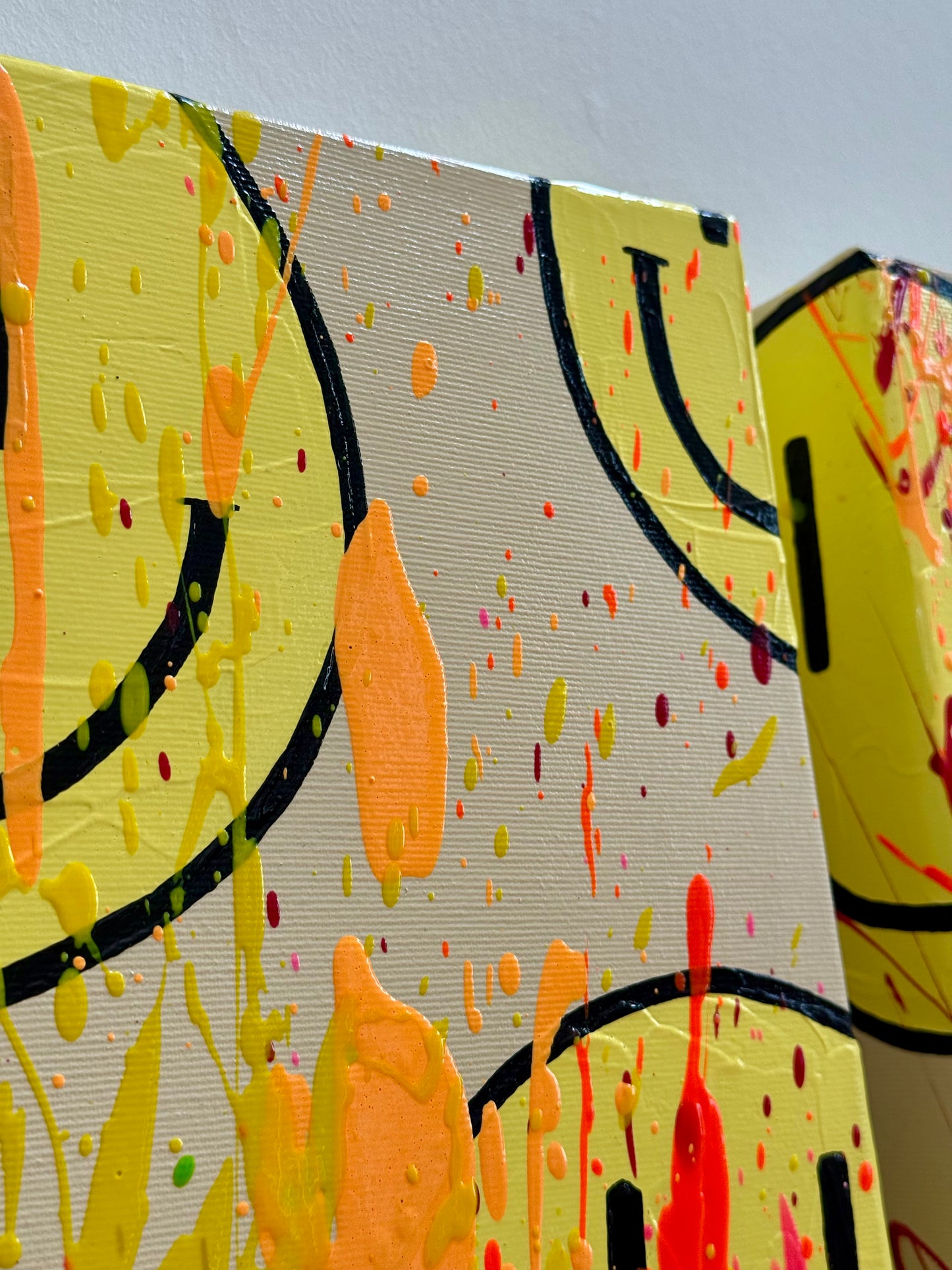 Seitenansicht von HAPPY #24 mit gelben Happy-Faces, Neonorange-, Apricot- und Gelbtönen sowie strukturreicher abstrakter Acrylmalerei auf Leinwand.